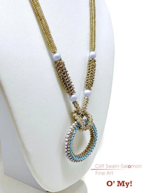 Gold and pearl necklace with a circular pendant, displayed on a white jewelry bust