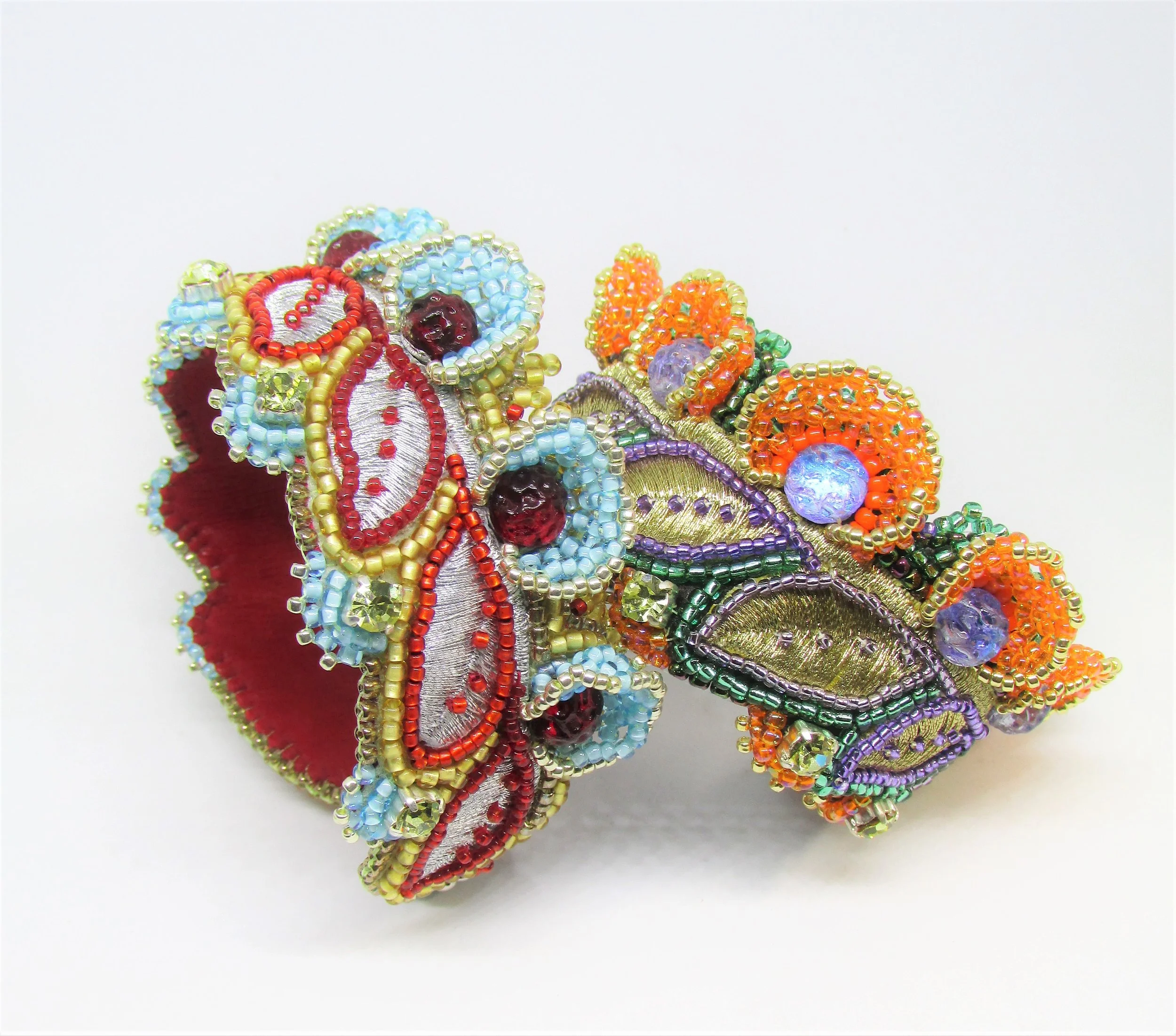 Close-up of a decorative piece made of colorful beads, sequins, and fabric, arranged in a floral pattern on a white background.
