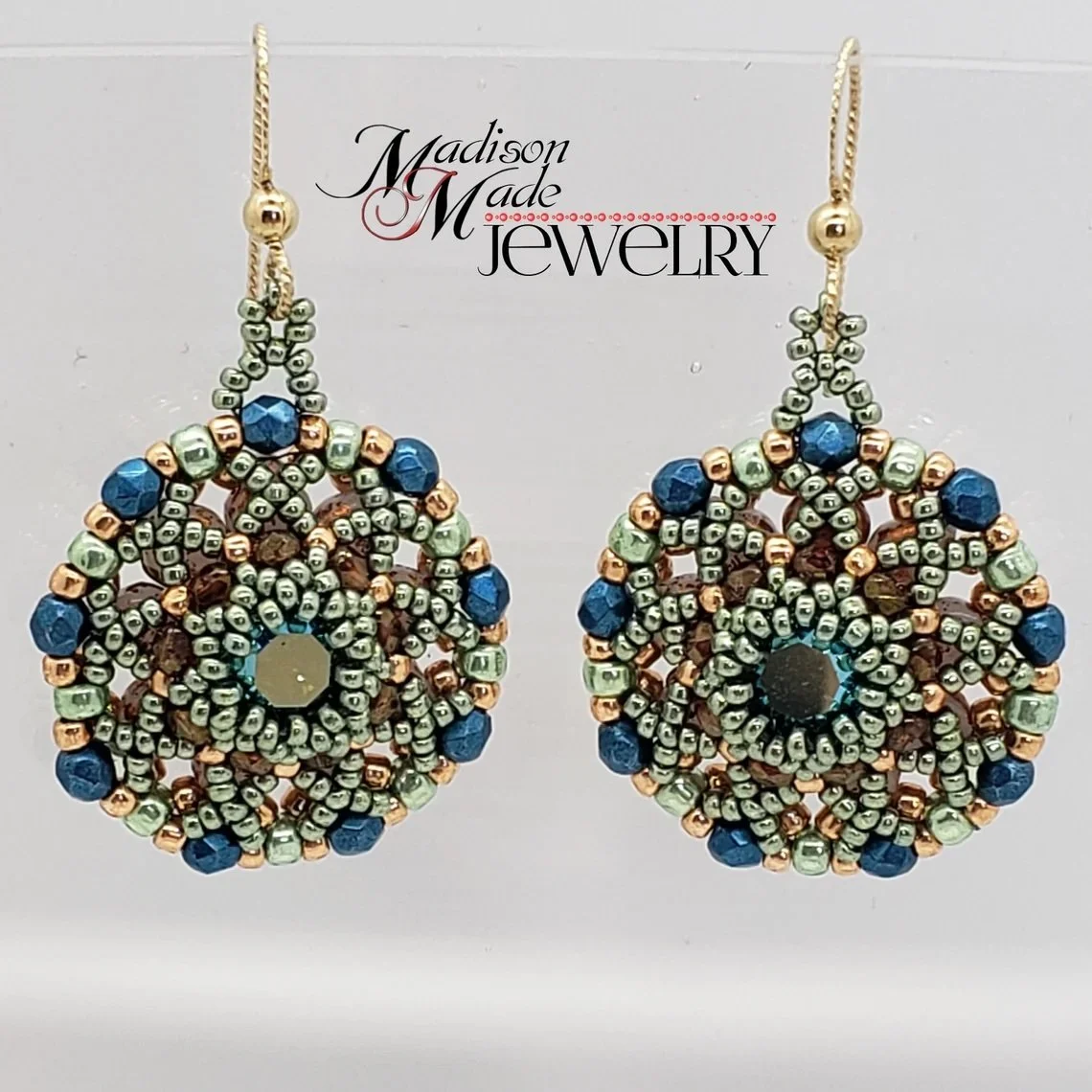 Pair of beaded dangle earrings with circular design, featuring green, blue, and copper-colored beads, on a white background with 'Madison Made Jewelry' text.