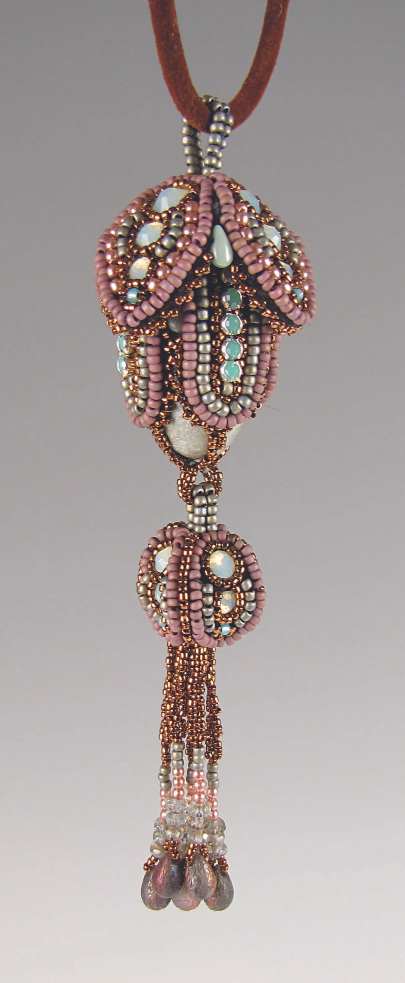 Beaded decorative pendant hanging from a brown cord.