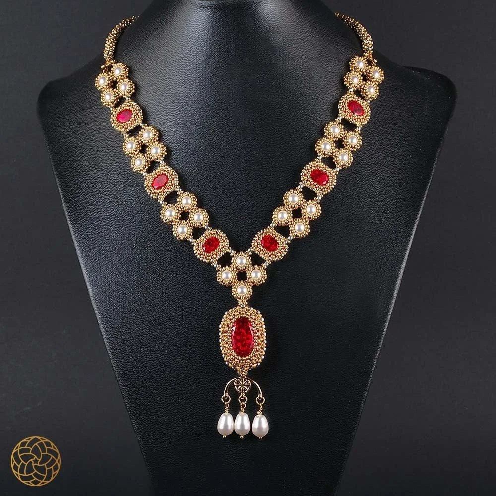 Gold and red beaded necklace with pearl accents on black display mannequin.