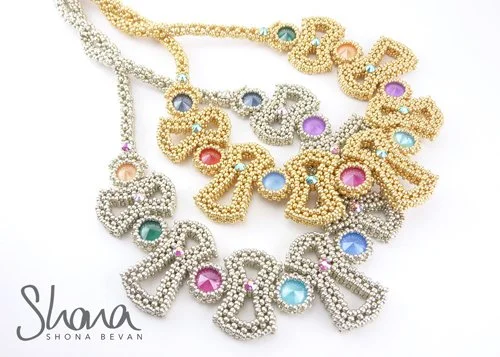 A collection of colorful, bejeweled necklaces with large, gold and silver chains and multicolored gemstone accents.