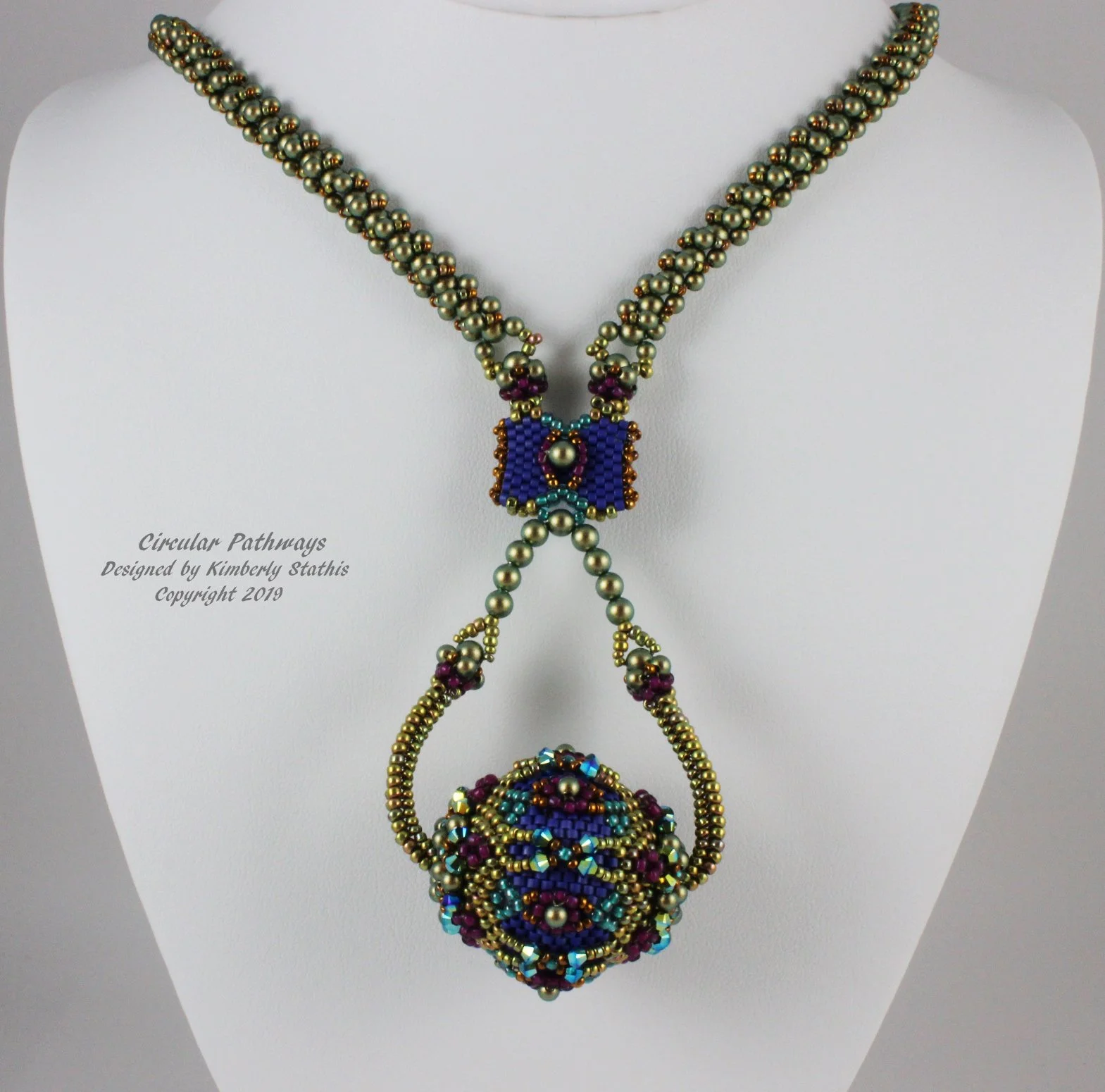 Beaded jewelry necklace and earrings on display, with a white background and a label that reads "Circular Pathways Designed by Kimberly Stathis Copyright 2019."
