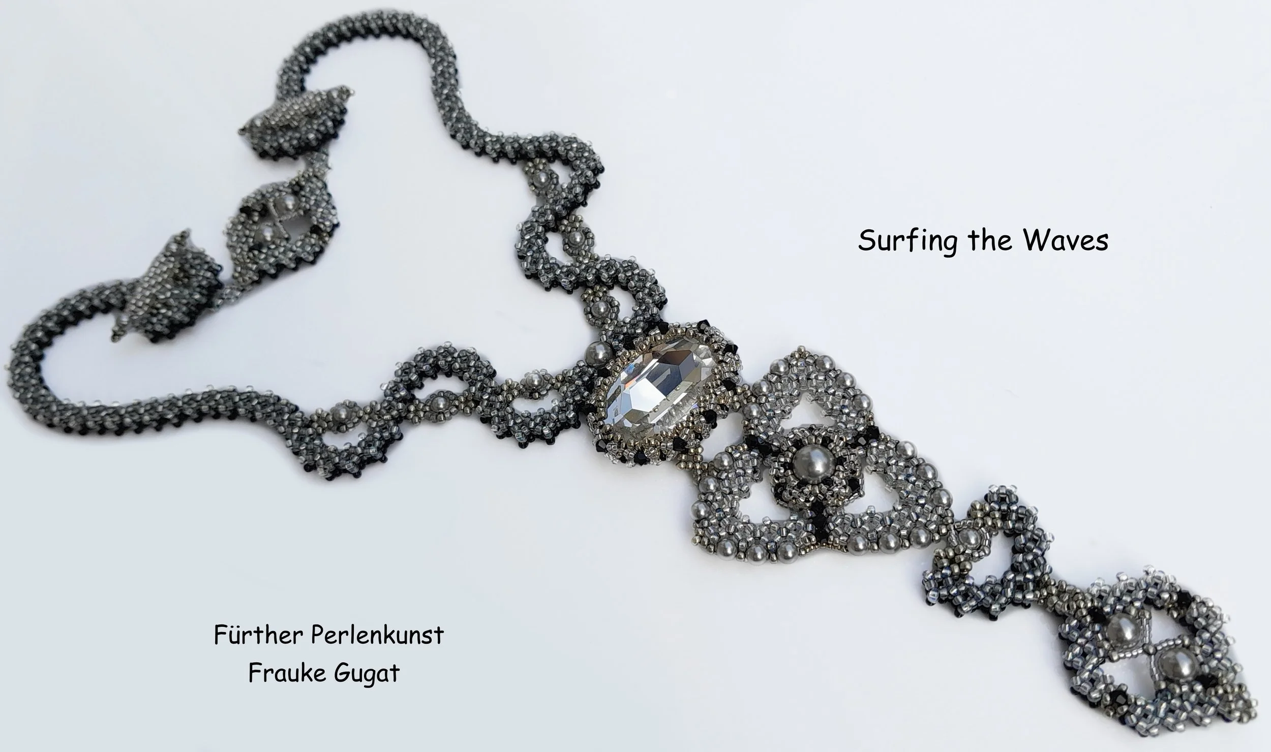 Close-up of a silver and black beaded necklace with large crystal pendant on a white background, titled 'Surfing the Waves'.