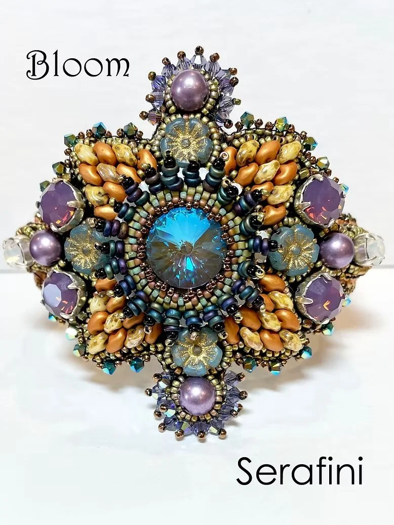 An ornate, colorful beaded brooch with a large blue gemstone at the center, surrounded by purple, tan, and black beads, and smaller gemstones. The words "Bloom" and "Serafini" are written on the image.