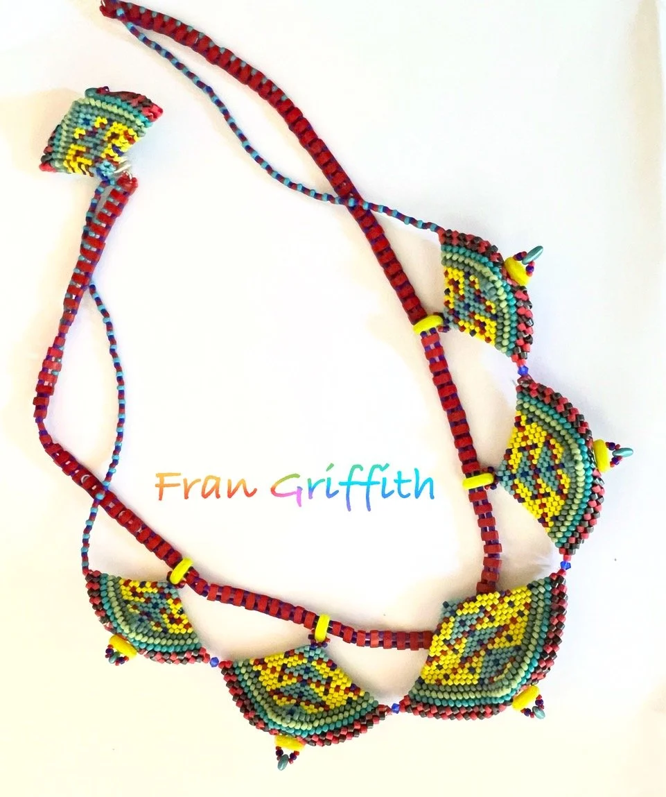 Colorful beaded necklace with leaf-shaped beads and small yellow accent beads, laid out on a white background with the name 'Fran Griffith' written below in rainbow-colored letters.