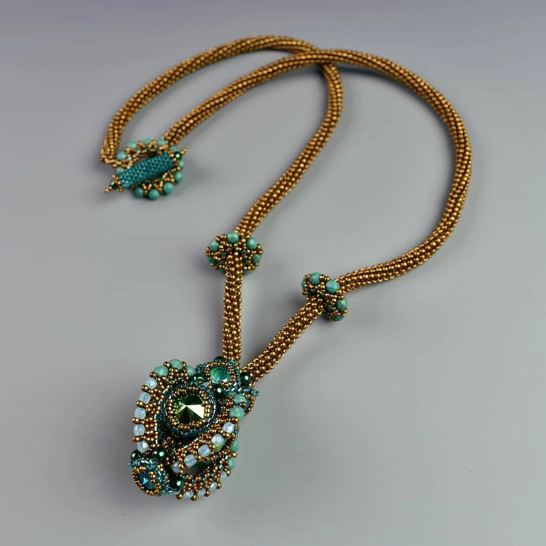 Gold and turquoise beaded necklace with a large ornate pendant and decorative beads.