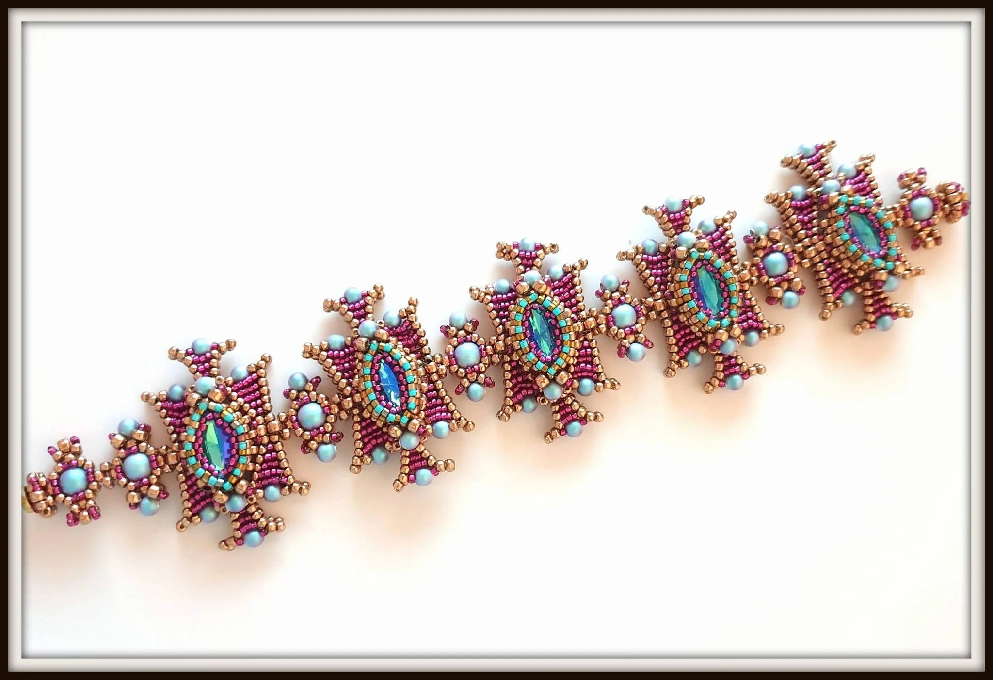 Close-up of a colorful beaded jewelry piece with pink, blue, green beads, and pearls on a white background.