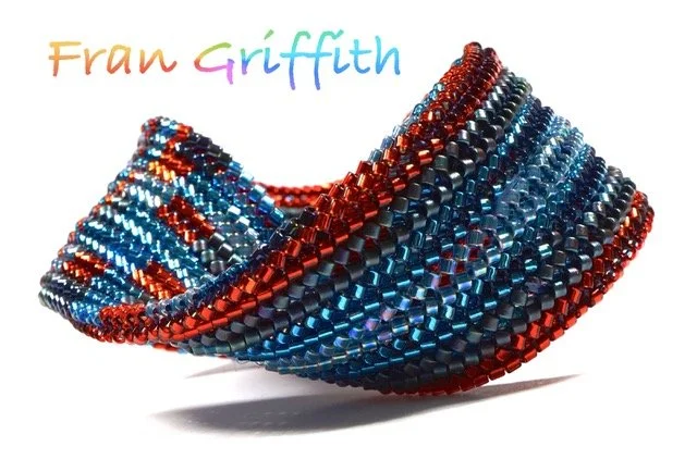 A colorful bead bracelet made of multiple strands of small, shiny beads in red, blue, black, and orange, arranged in a twisted pattern.