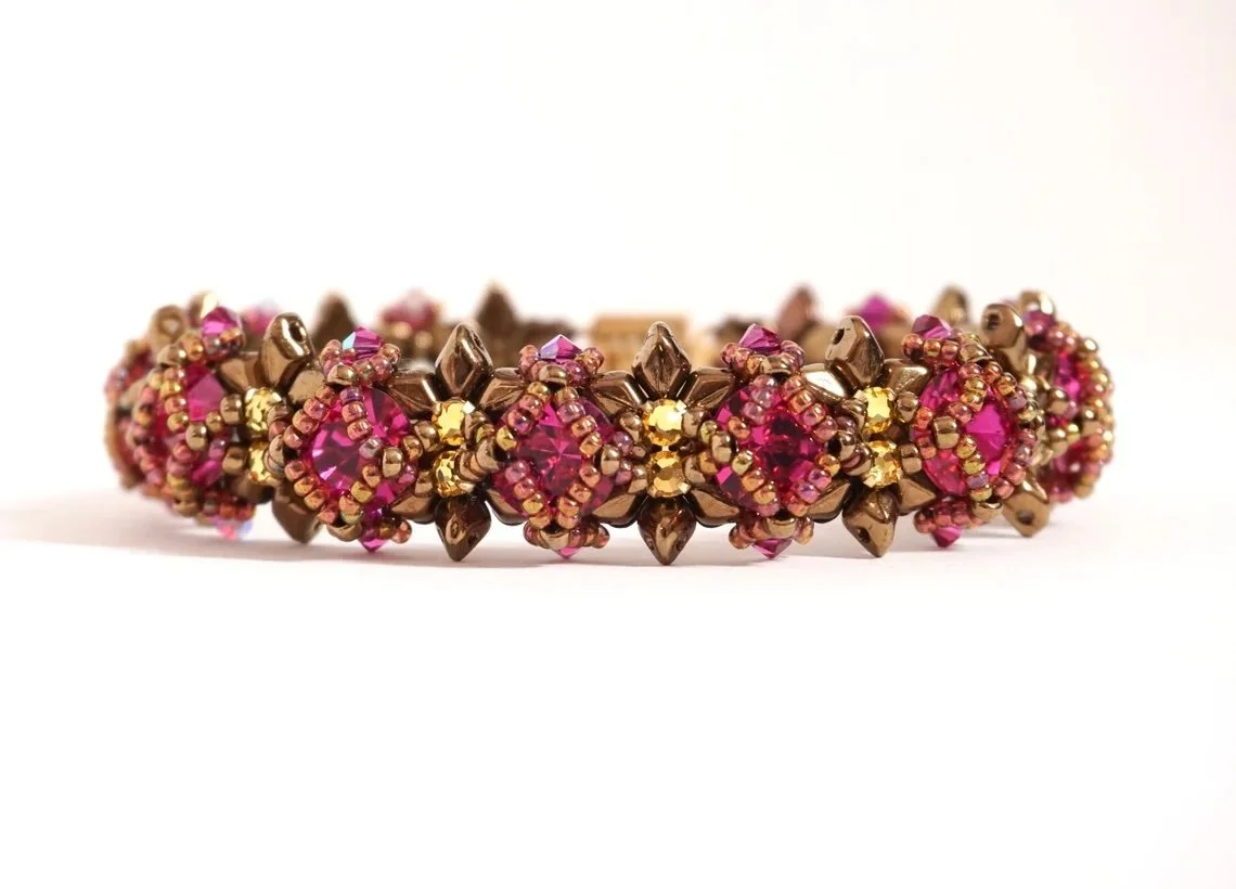 Close-up of a bejeweled bracelet with pink and yellow stones set in a gold and brown metal band.
