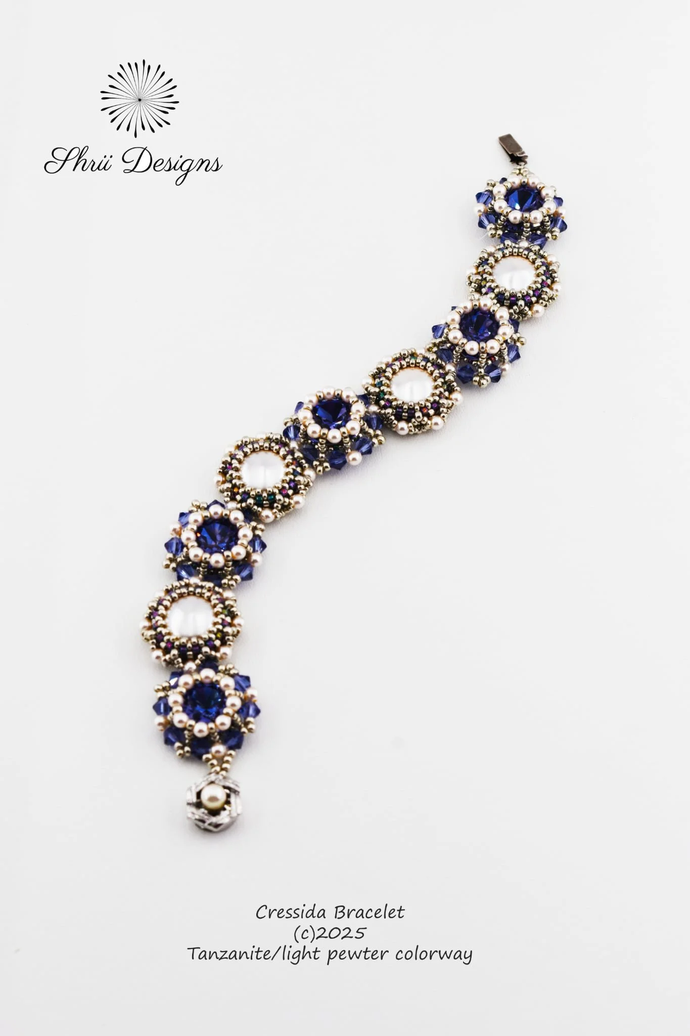 Close-up image of a beaded bracelet with dark blue and pearl beads, labeled 'Cressida Bracelet, Tanzanite/light pewter colorway, 2025'.