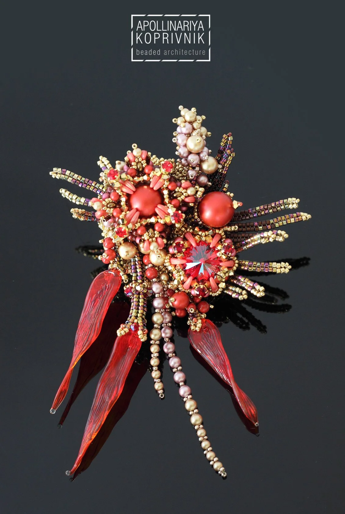 Beaded jewelry brooch with red, pink, and gold beads, featuring glass and gemstone accents, designed to resemble a floral or abstract motif.