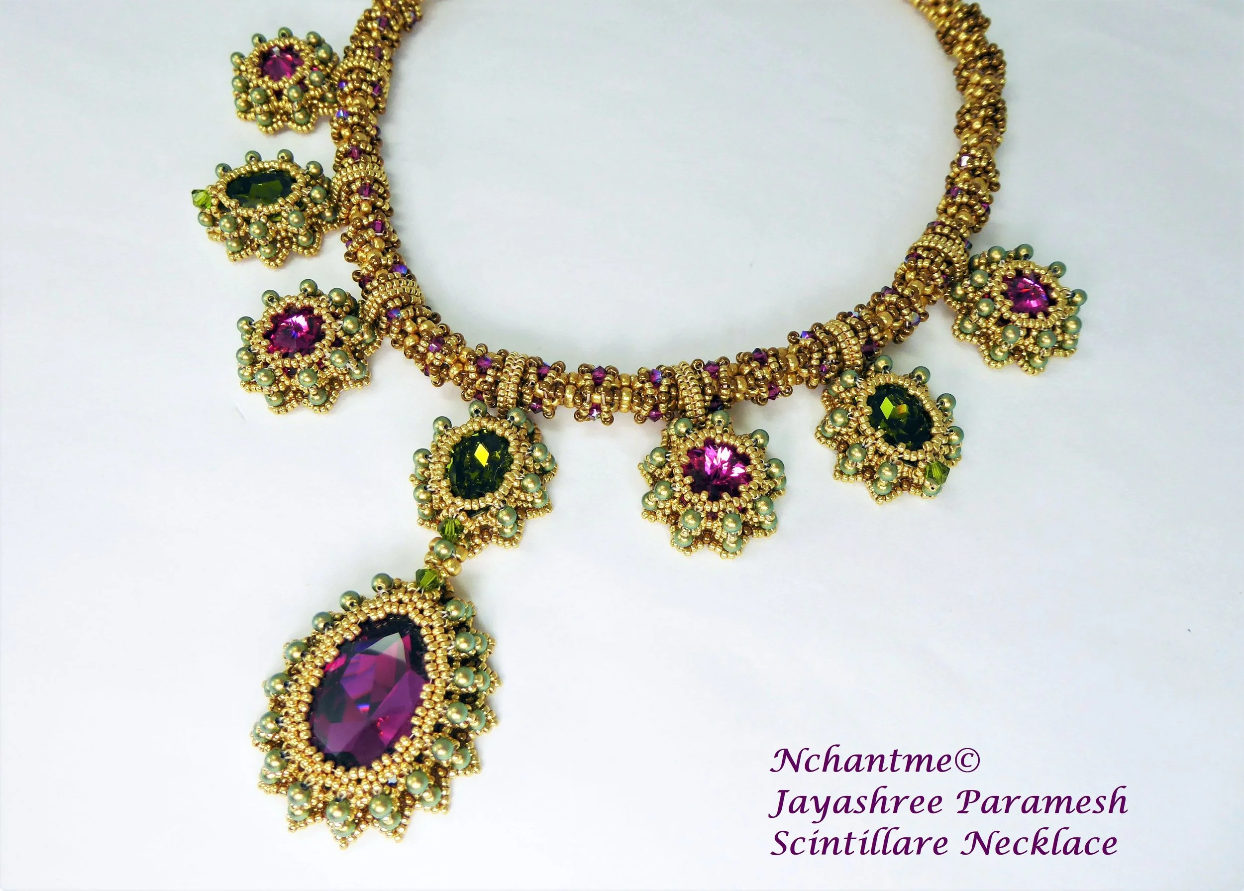 A gold and gemstone necklace with purple, green, and pink stones, featuring intricate beaded design and floral motifs, displayed against a white background.