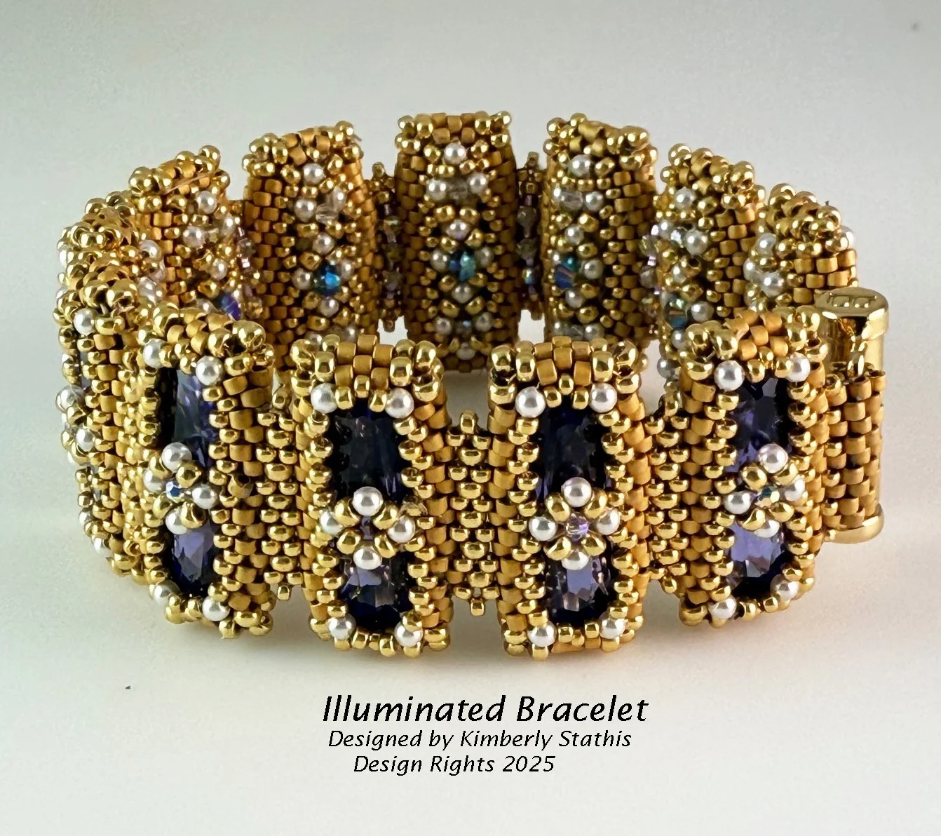 Gold bracelet decorated with dark blue gemstones, small white pearls, and gold beads, designed by Kimberly Stathis in 2025.