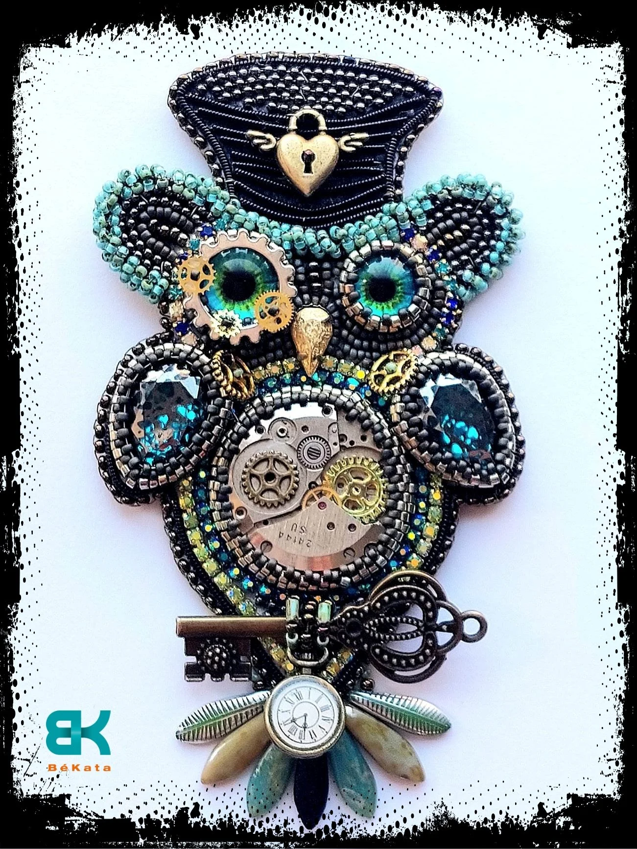 A steampunk-style owl pendant made of various beads, gears, and watch parts, featuring green eyes and a padlock with wings at the top, set against a white background.