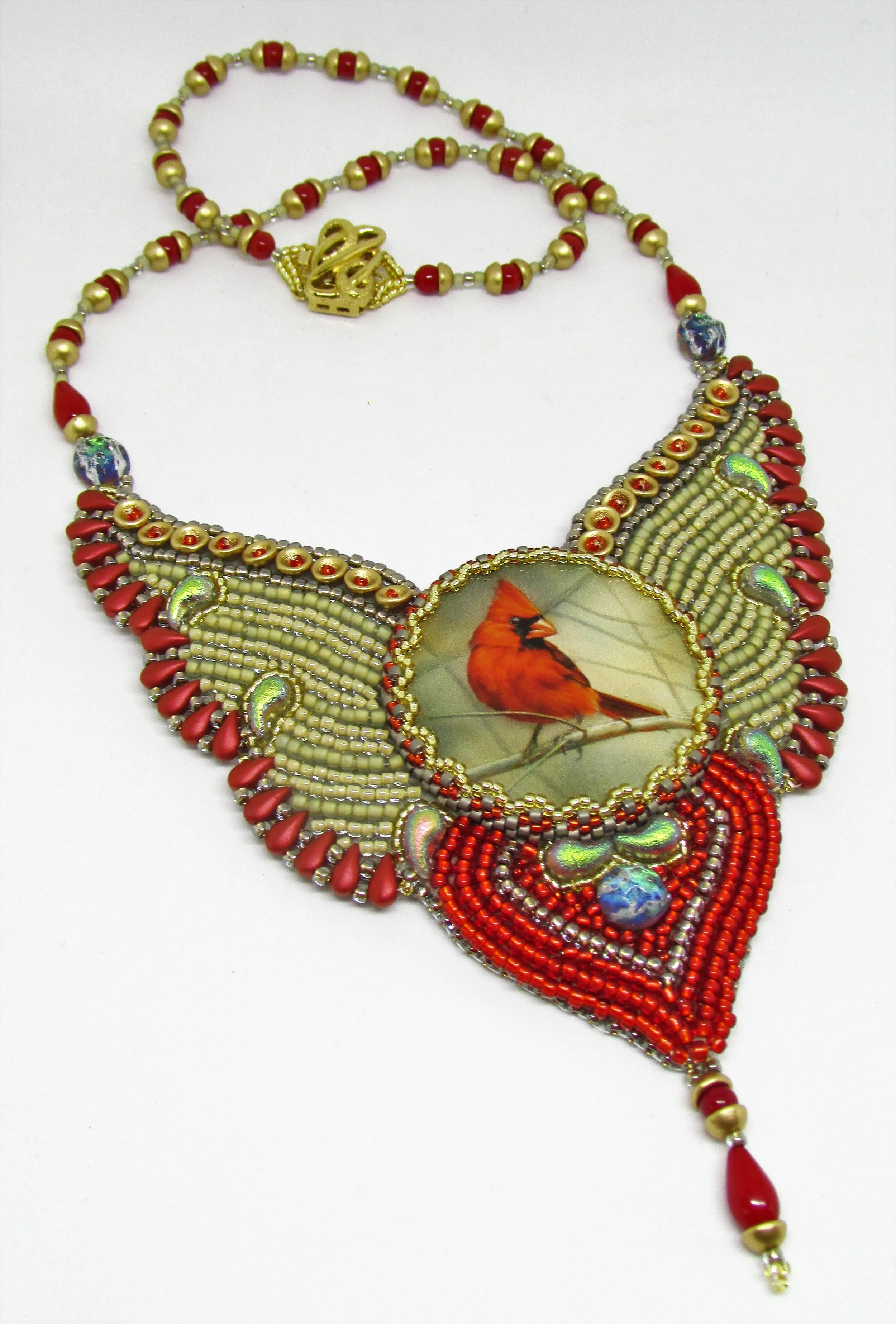 Beaded necklace with red and gold beads, an oval pendant with a bird illustration, and decorative beads, on a white background.