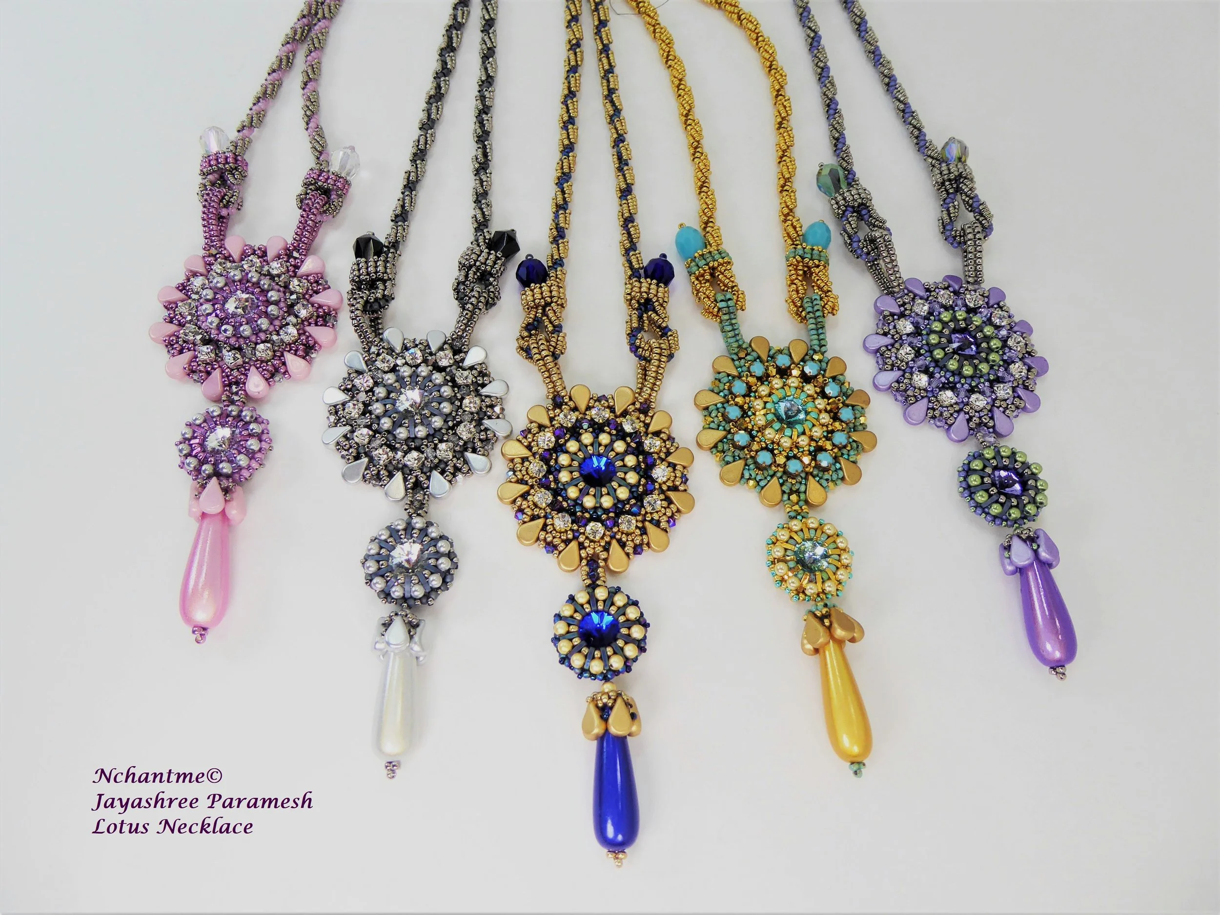 Colorful lotus-shaped necklaces with intricate beadwork and dangling teardrop pendants, arranged in a line on a white background.