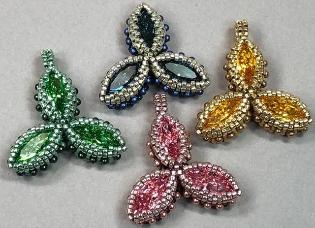 Four butterfly-shaped pendants in green, blue, pink, and yellow with crystals and metal beads.