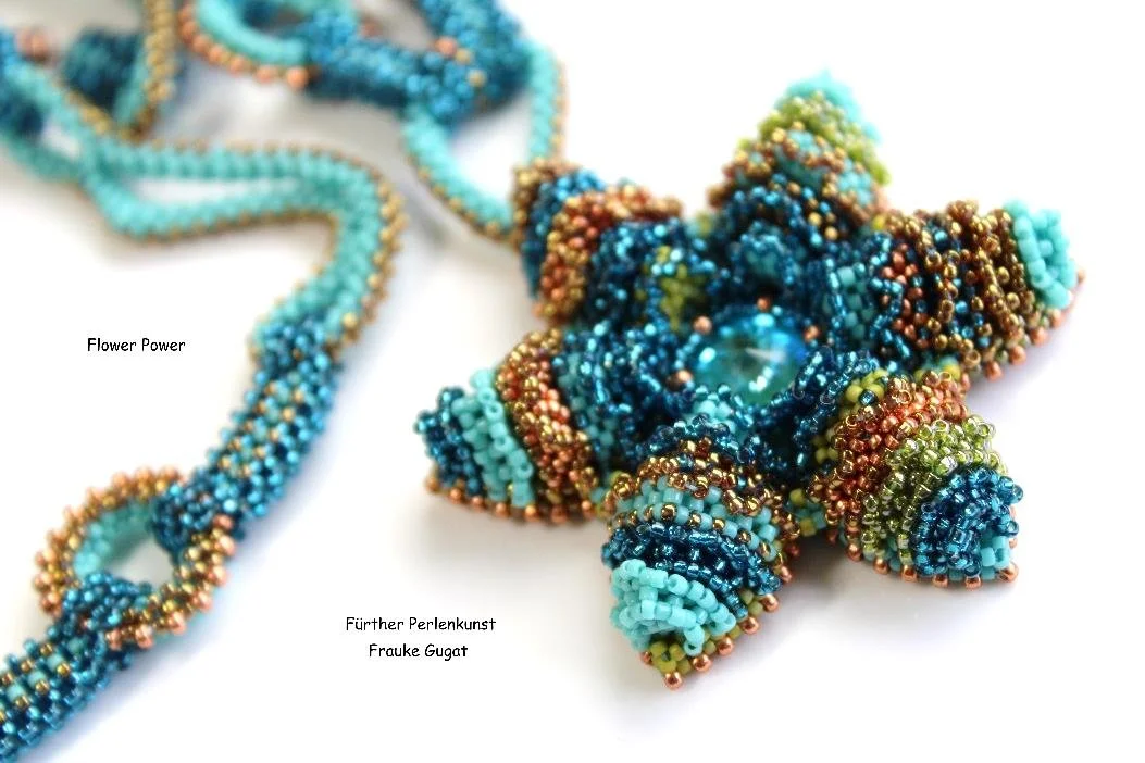 Close-up of a colorful bead necklace and a beaded star-shaped pendant, with small text labels reading 'Flower Power' and 'Fürther Perlenkunst Frauke Gugat'.