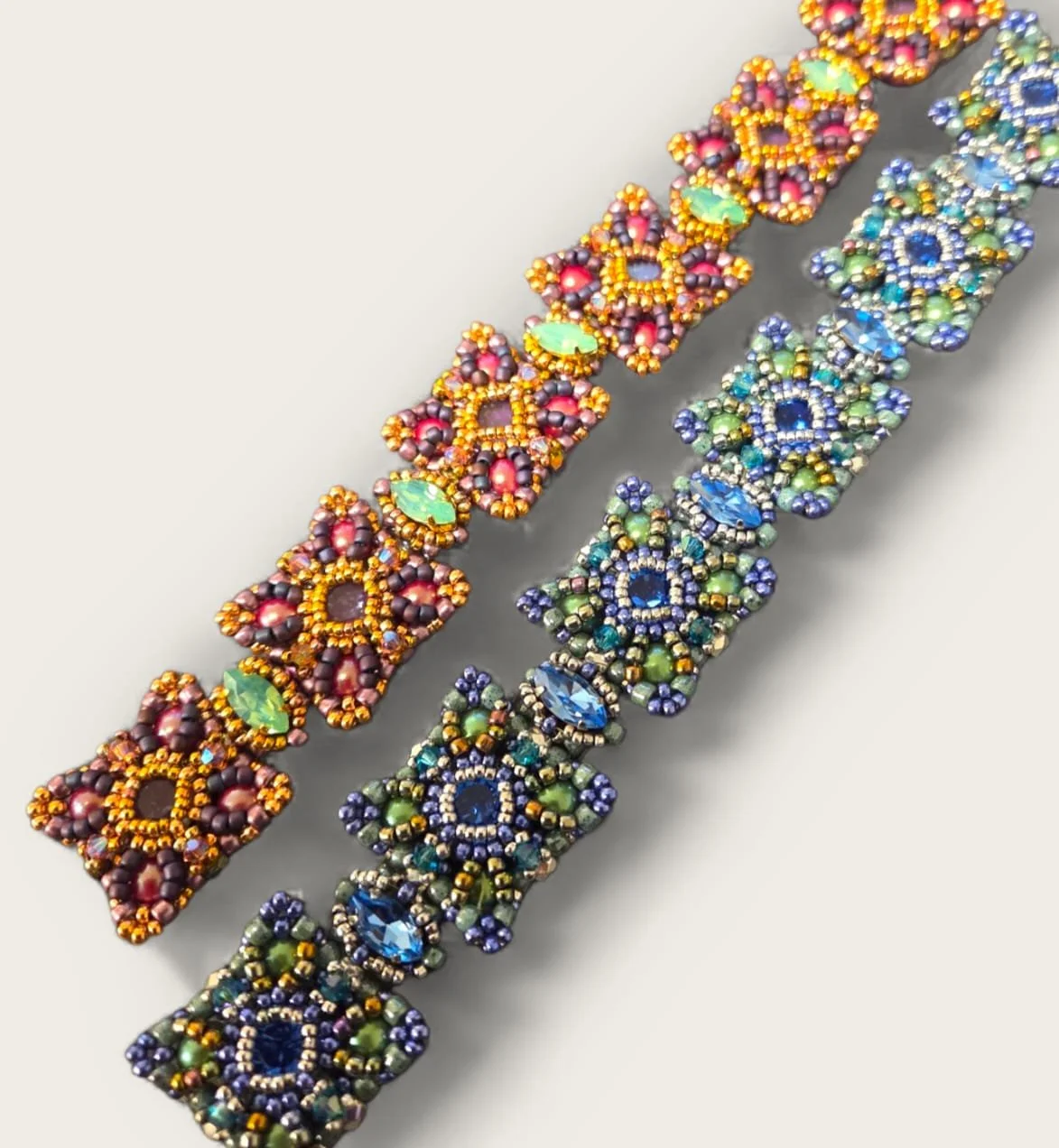 Two ornate beaded bracelets with intricate patterns in vibrant colors, including orange, green, blue, purple, and gold beads.