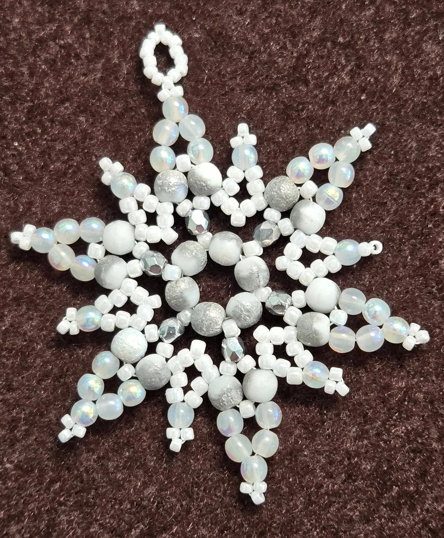 Collection of white pearl and frosted glass bead necklaces and bracelets on a dark brown textured surface.