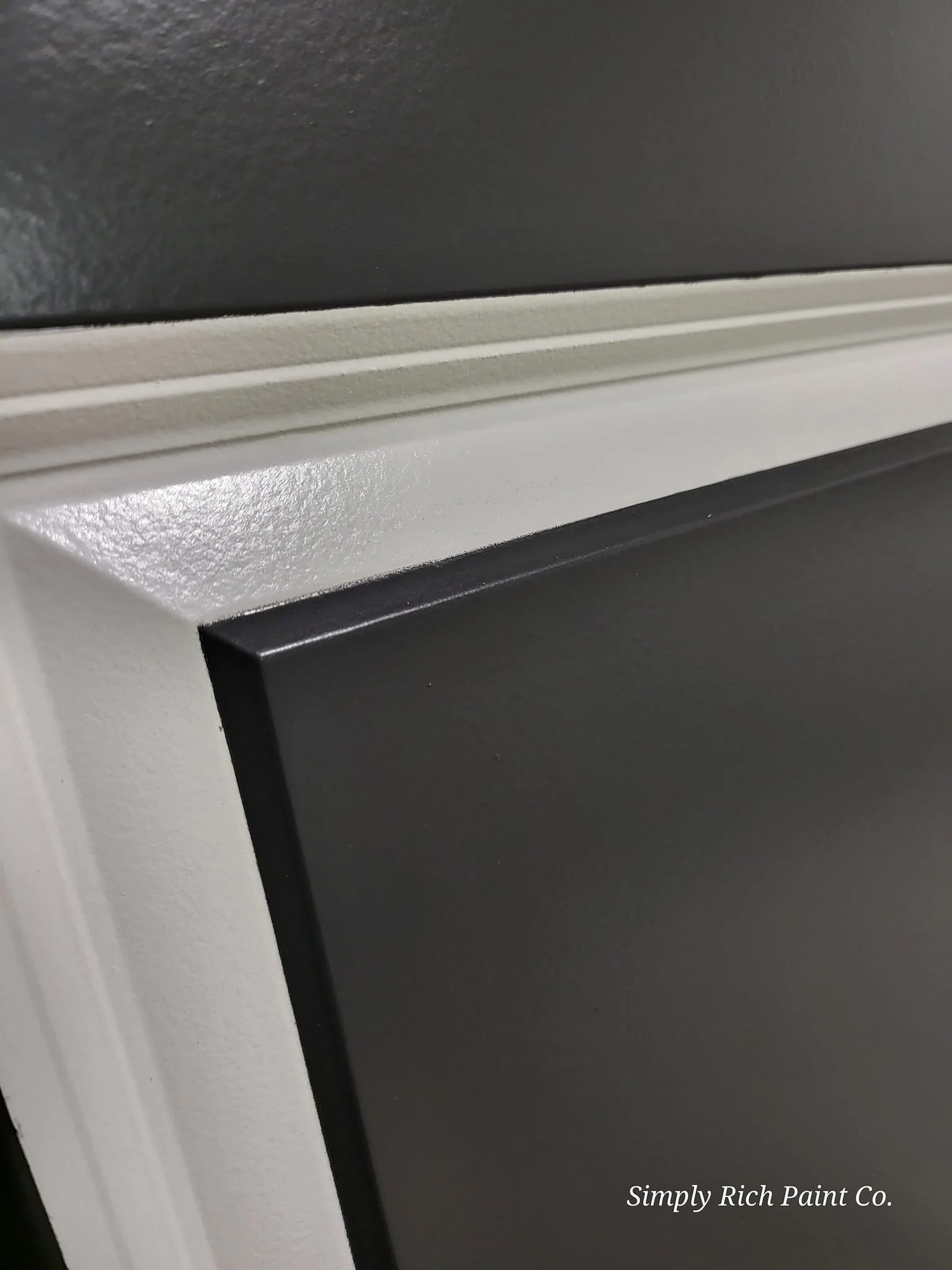 Close-up of a painted cabinet corner with black, beige, and white colors, and the text "Simply Rich Paint Co." in the bottom right corner.
