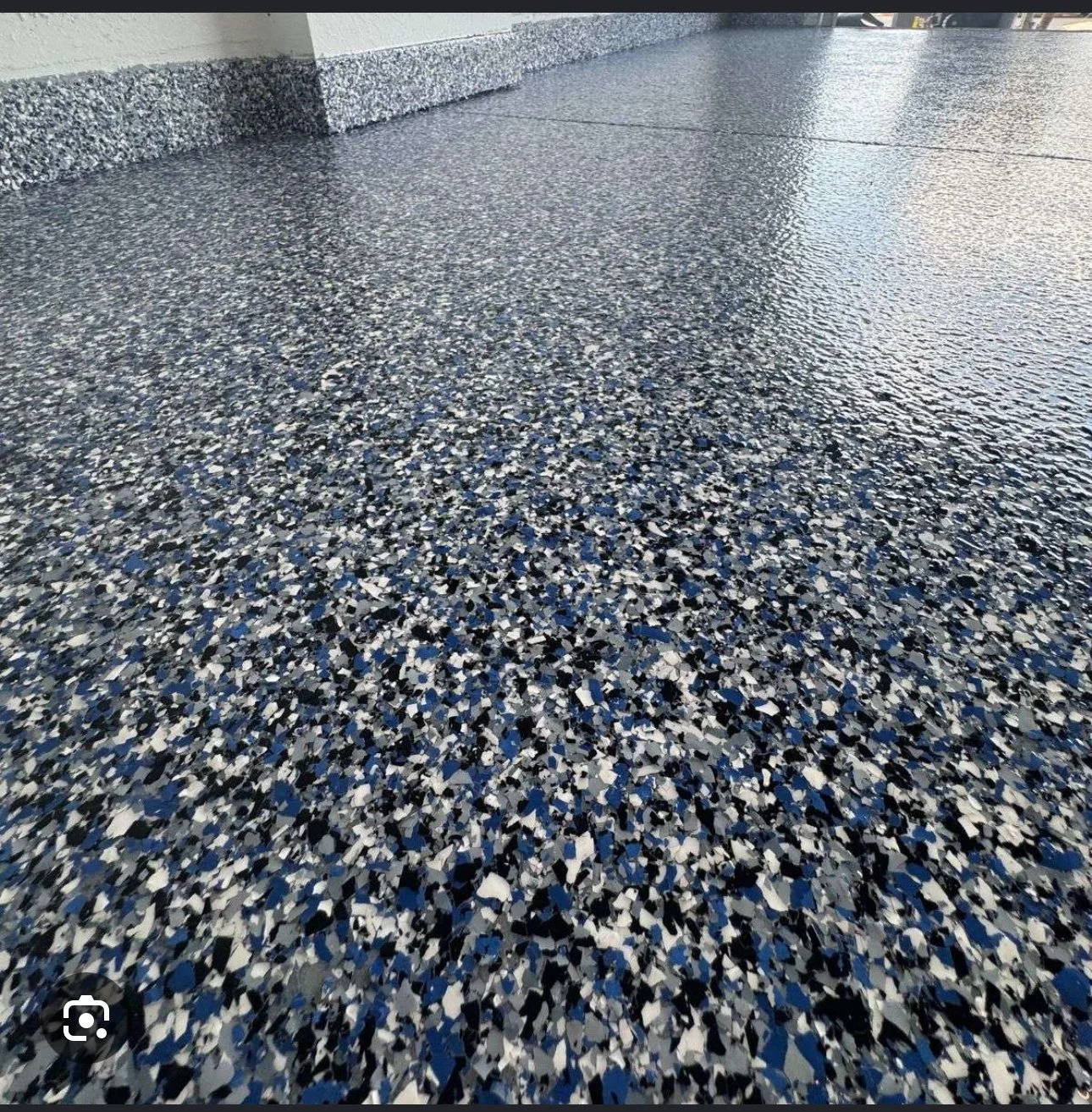 Epoxy floor with blue, black, gray, and white speckled terrazzo pattern