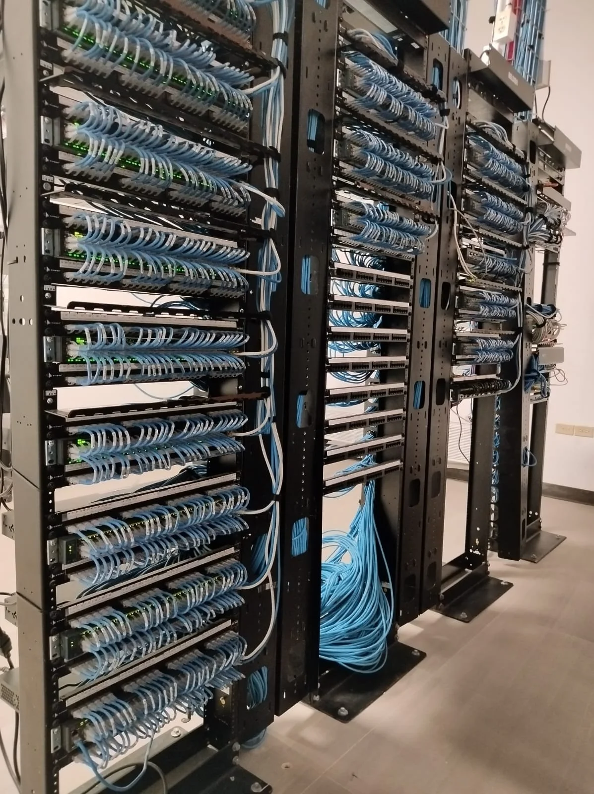 Row of server racks with numerous tangled blue and white Ethernet cables in a data center or server room.