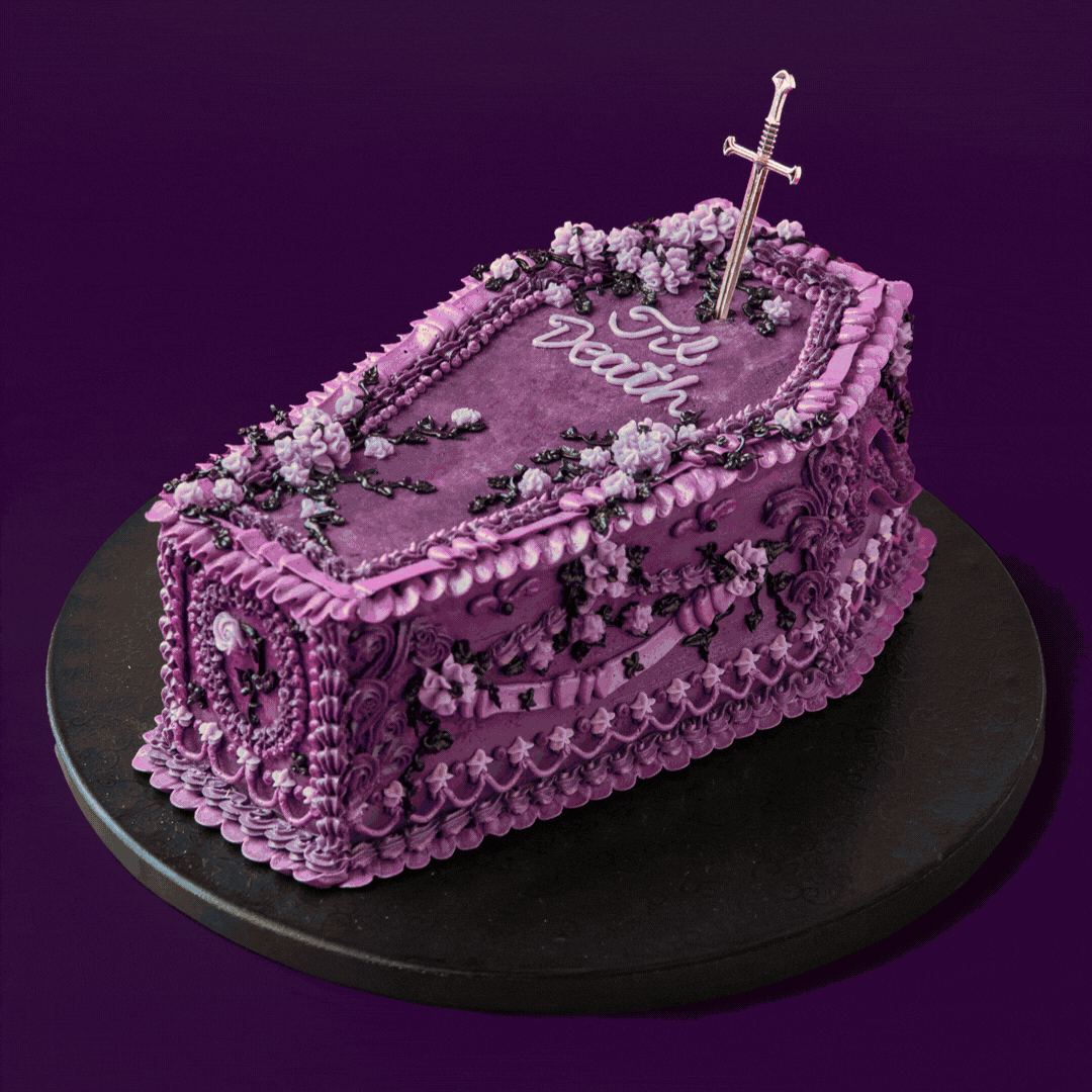 Colorful decorated cake with fondant flowers and pearls on a purple background.