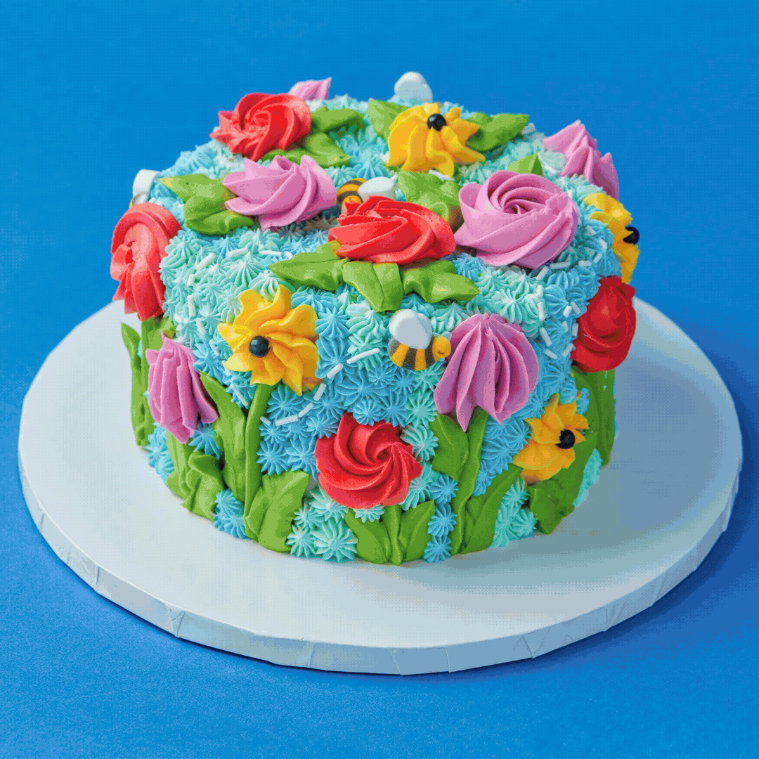 Colorful decorated cake with fondant flowers and pearls on a purple background.