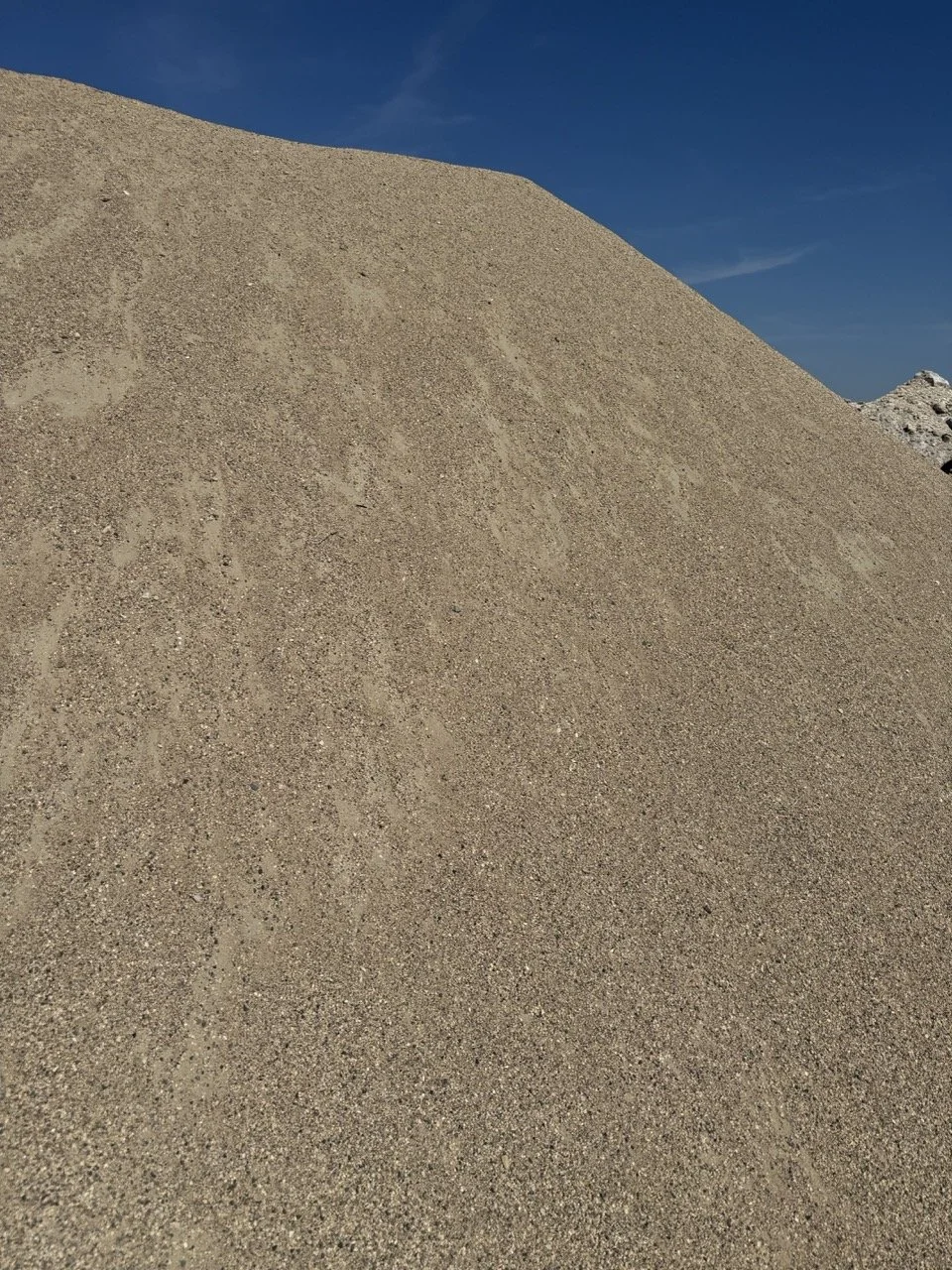 Close-up of a large pile of sand against a blue sky.