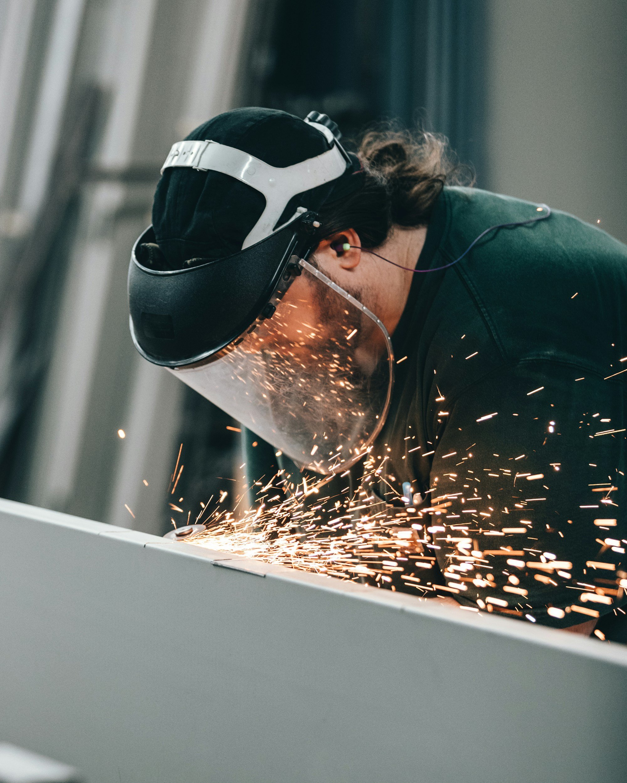 Worker using a grinder on site, with protective gear and visible sparks during metalwork.