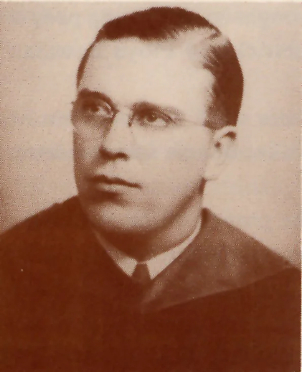 Black and white photograph of a young man with glasses, dressed in a formal academic gown, looking slightly to the side.