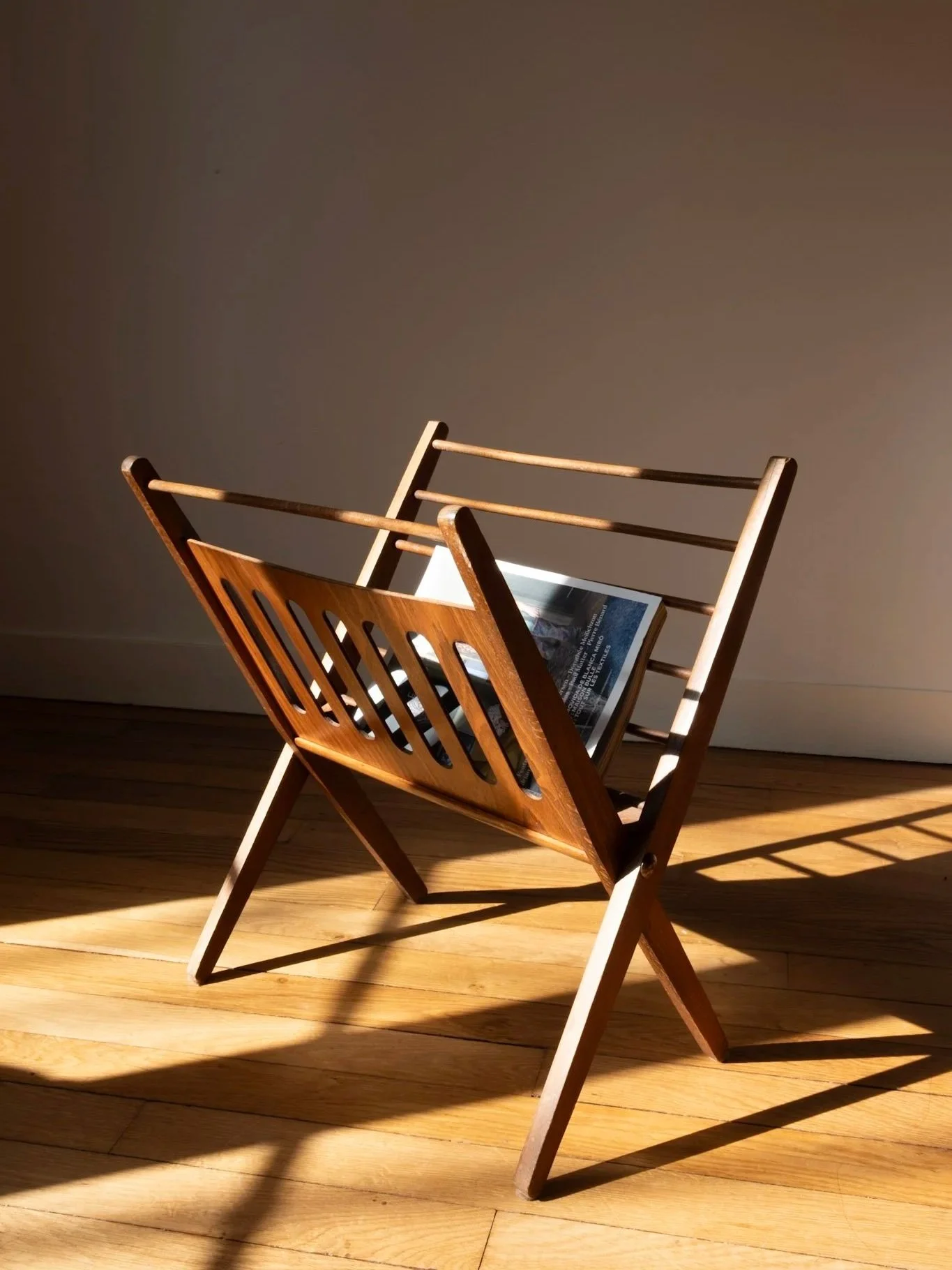 vue d'ensemble sur ce beau porte-revues pliant en bois vintage des années 50 présenté avec un magazine pour le mettre en situation