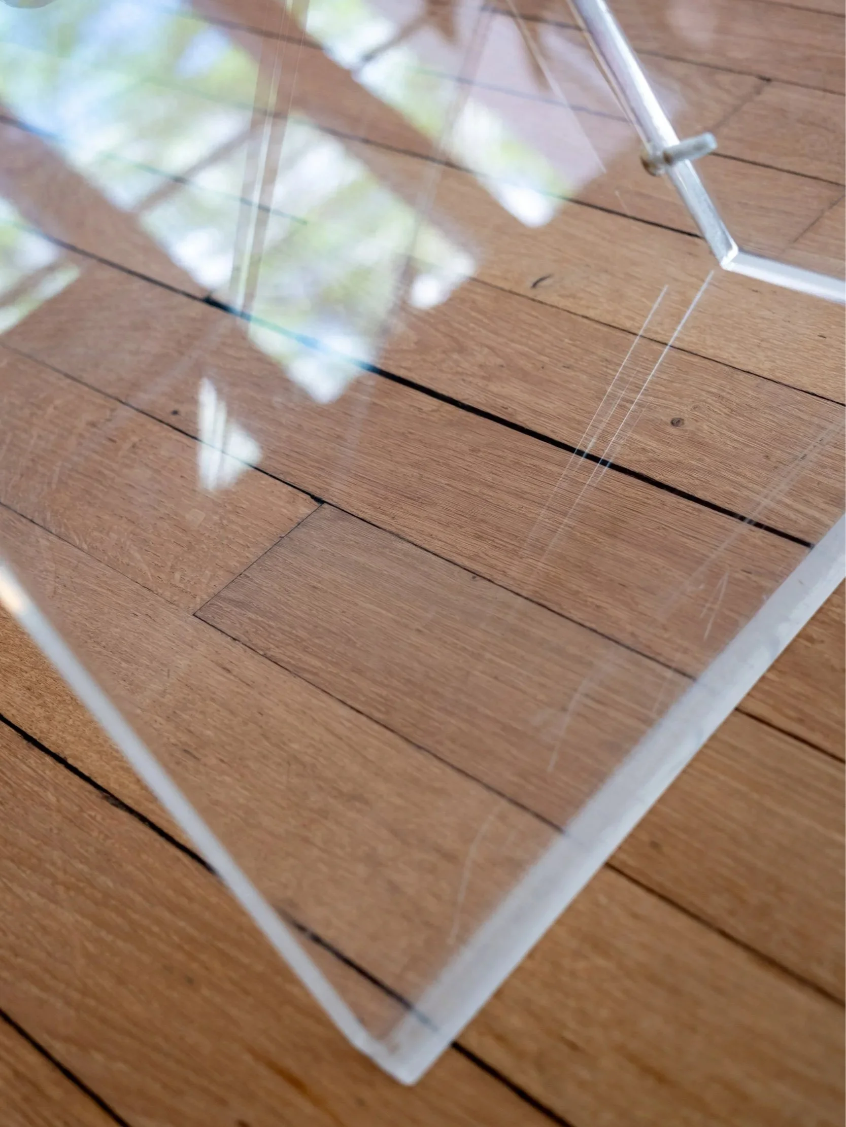 zoom sur le piètement en plexiglas de la table basse qui présente de légères rayures