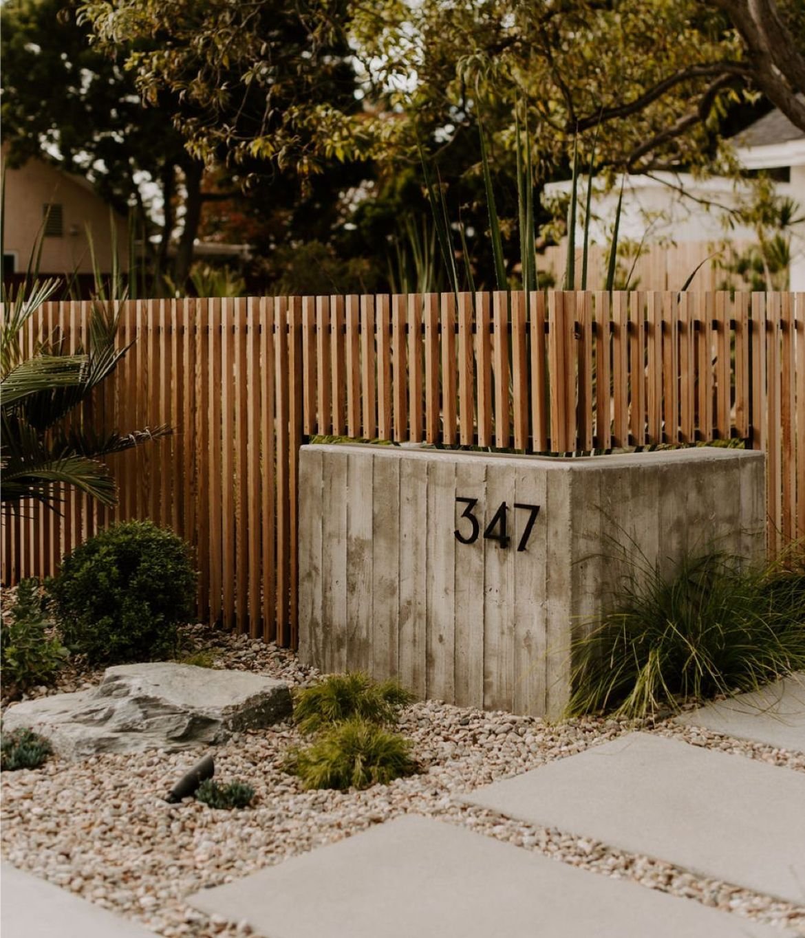 Residential house number 347 on a modern concrete wall with wooden fencing and landscaped garden in front.