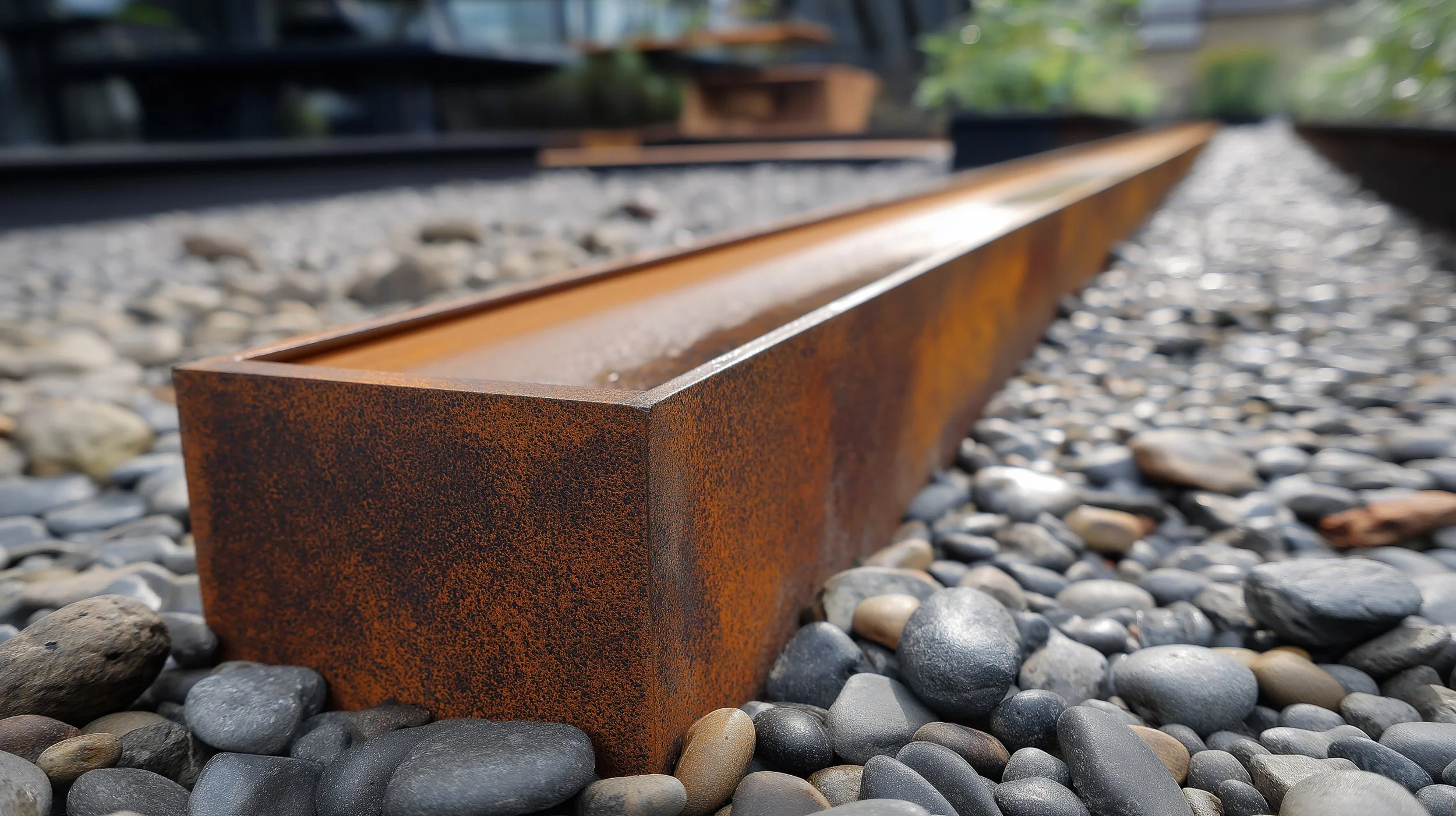 Close-up of rusted railroad track with gravel and small stones underneath, extending into the background.