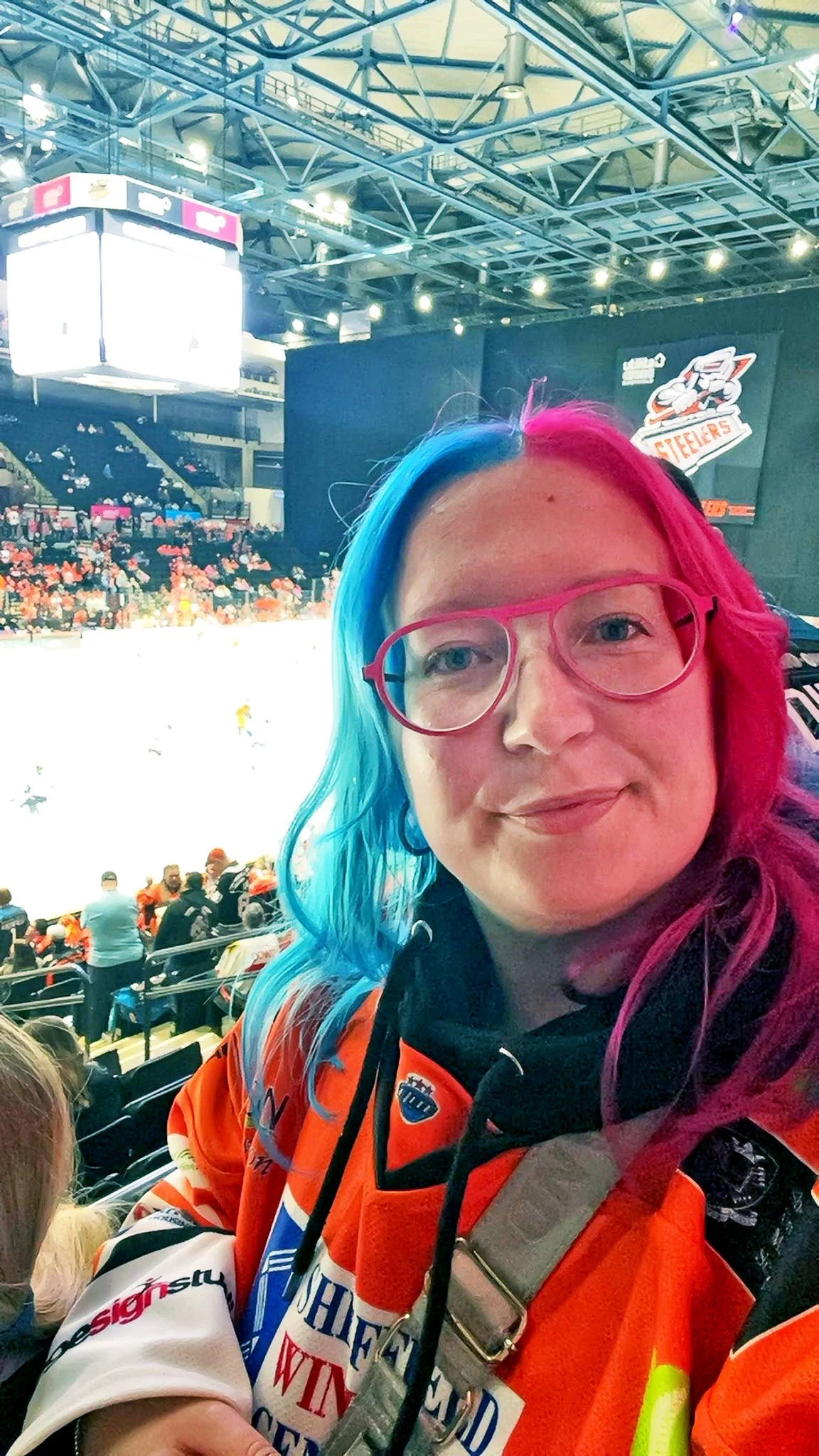 Hannah, smiling inside an ice hockey arena during a game.