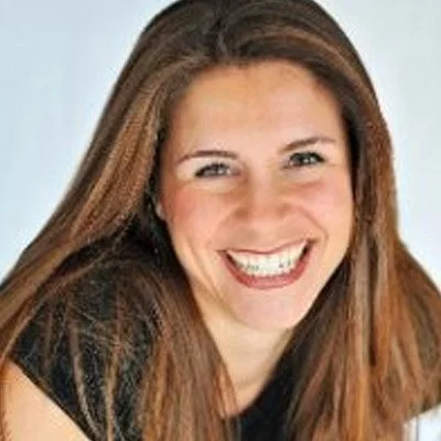 A woman with long brown hair smiling.