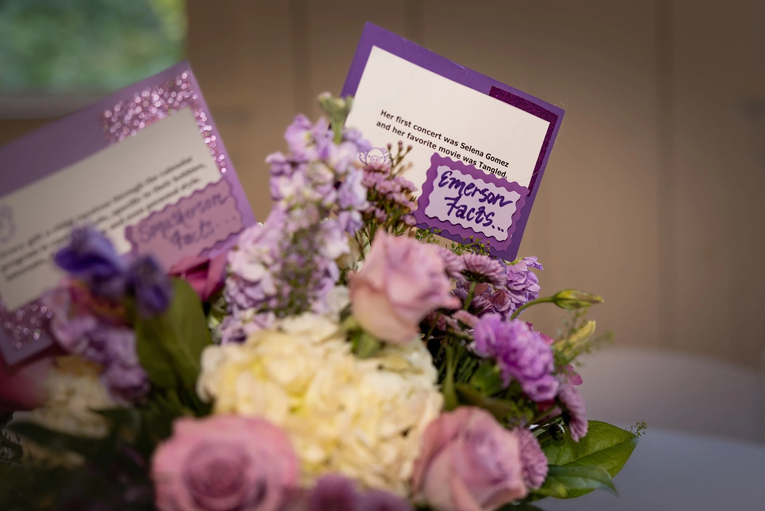 A floral arrangement with purple, pink, and yellow flowers, and a card reading about Selena Gomez and her movie 'Tangled.'