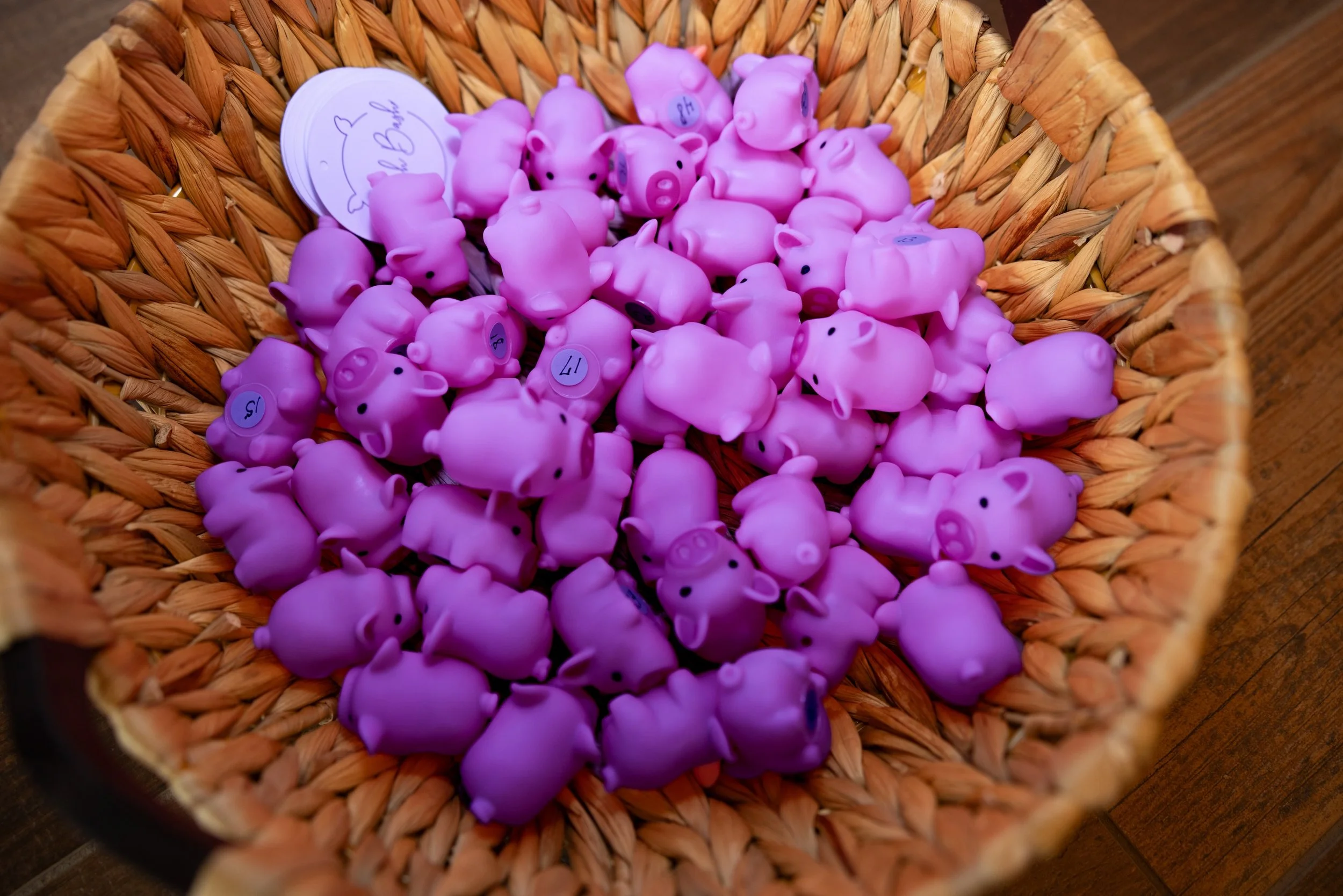 Pink pig-shaped rubber toys in a woven basket.