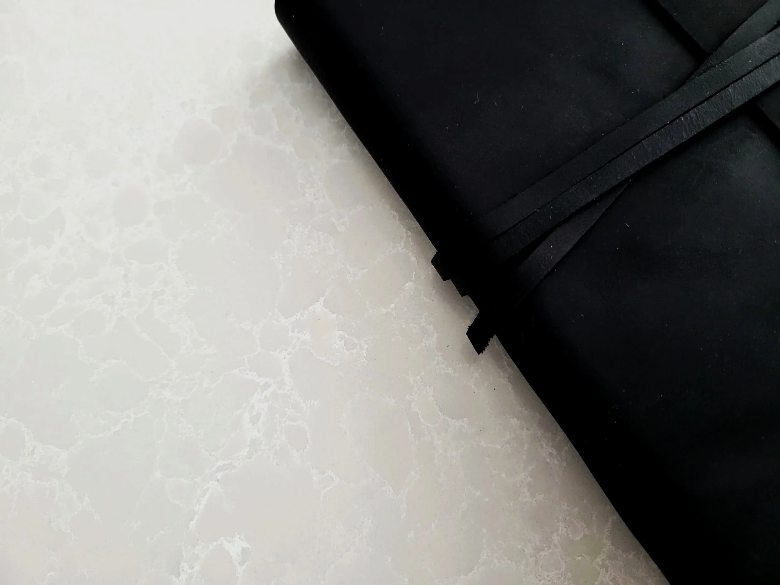 Close-up of a black briefcase resting on a white marbled surface.