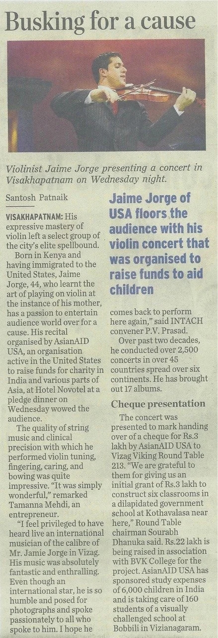 A newspaper clipping showing a man in a suit playing the violin, accompanied by an article about his charity concert to raise funds for children.