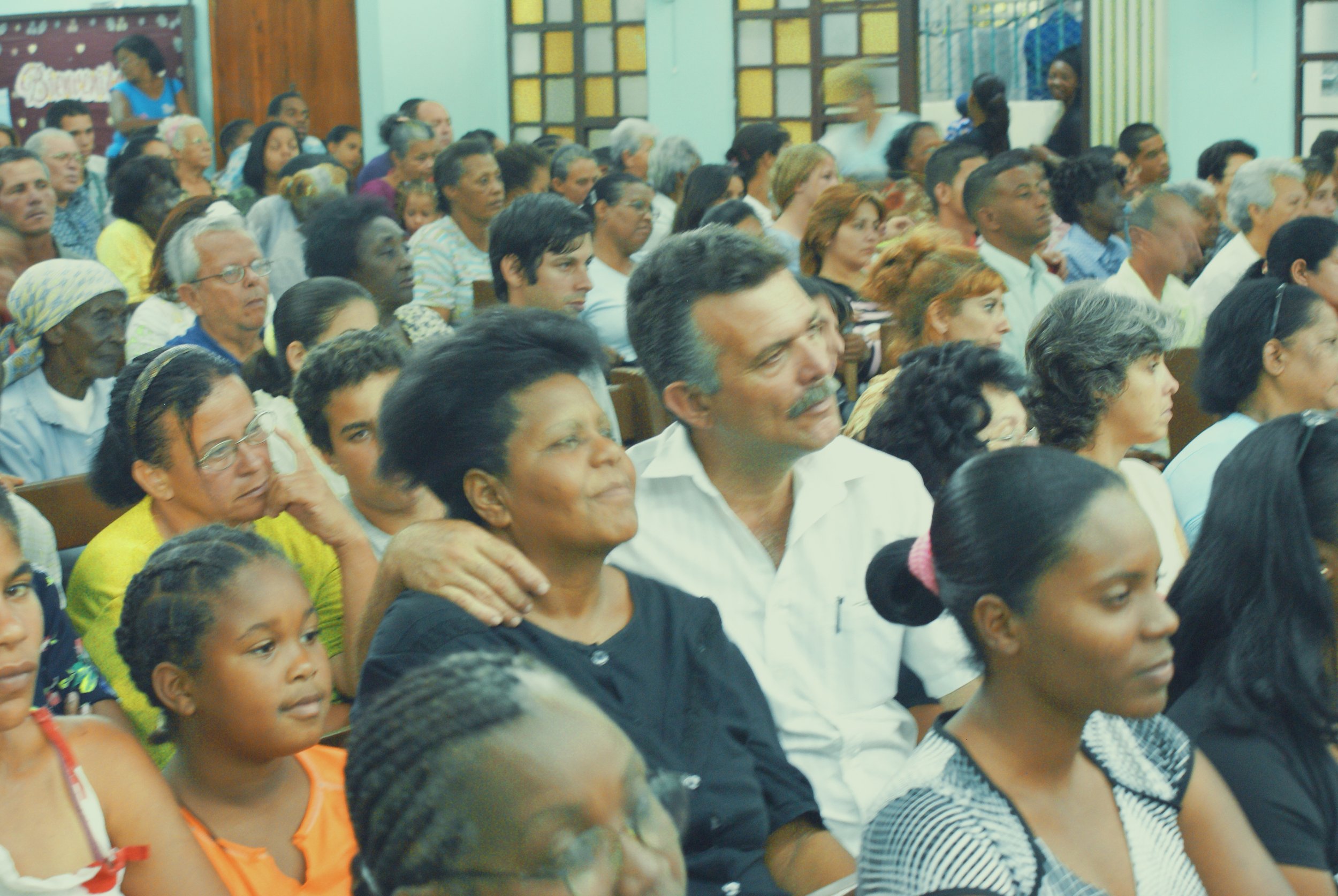 A diverse group of people seated indoors, attending a gathering or event.