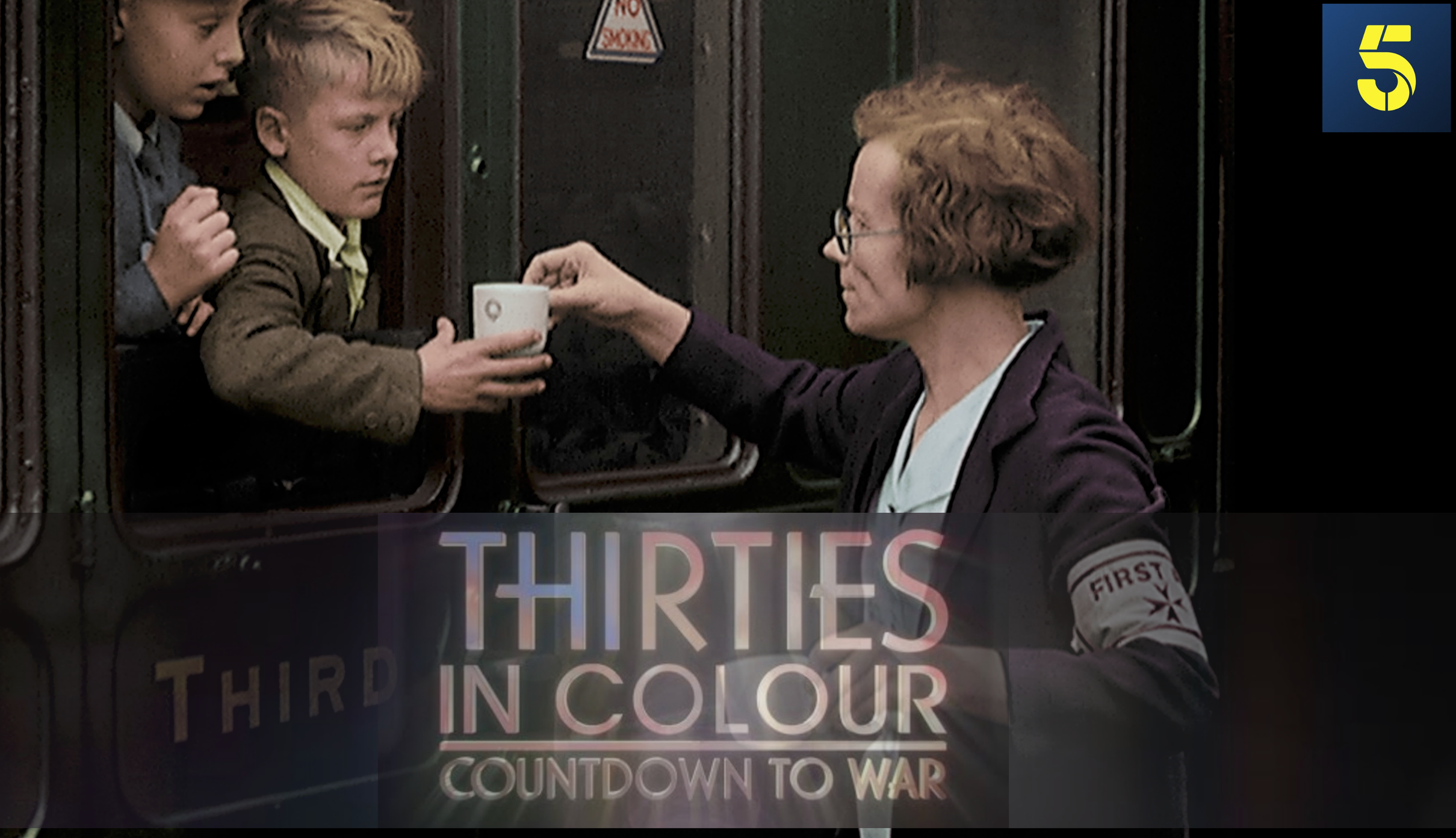 A woman wearing glasses and a jacket with a First First AID patch on her sleeve hands a cup to a boy through a subway train window, while another boy looks on from inside the train. A sign on the train reads "THIRTEENS" and some partial text mentions