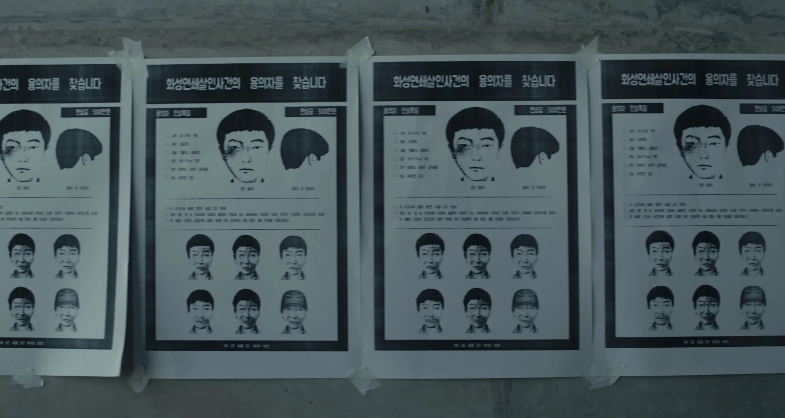 Multiple posters with black-and-white portraits of a woman and several men, all with East Asian features, taped to a wall.