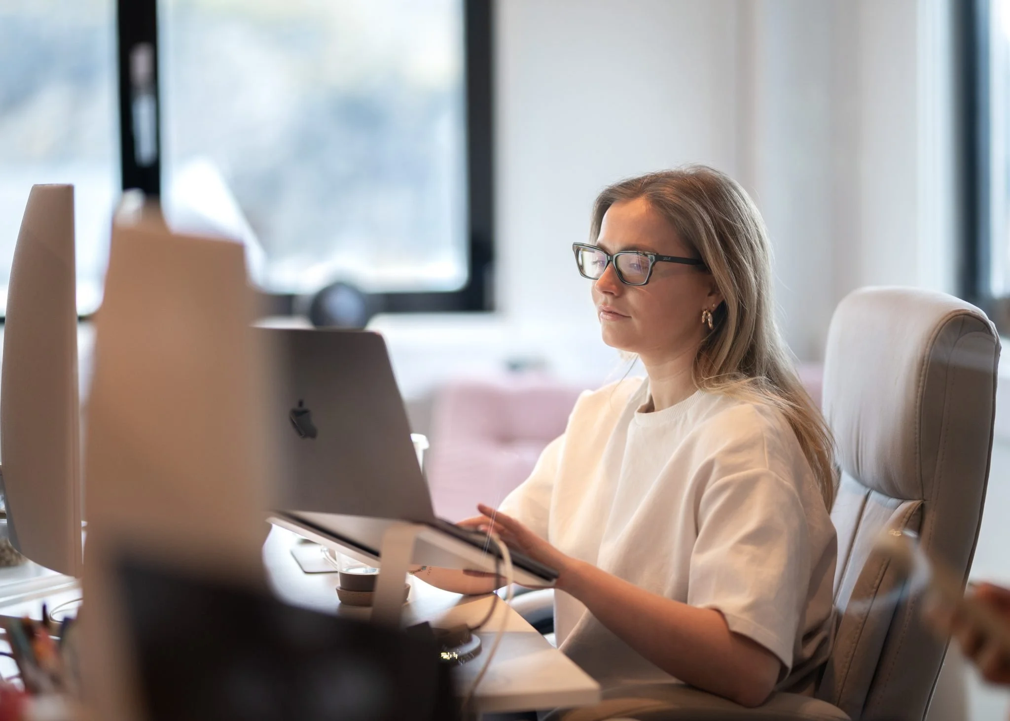 Kvinne med briller jobber på datamaskin på kontor.