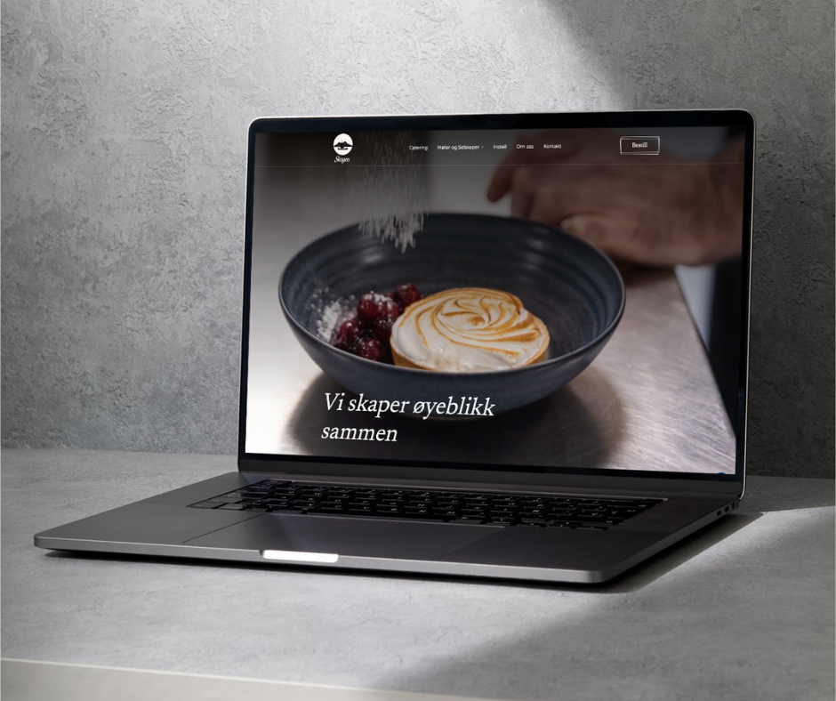 En åpen datamaskin på et skrivebord som viser en nettside med bilde av en dessert og teksten "Vi skaper øyeblikk sammen".