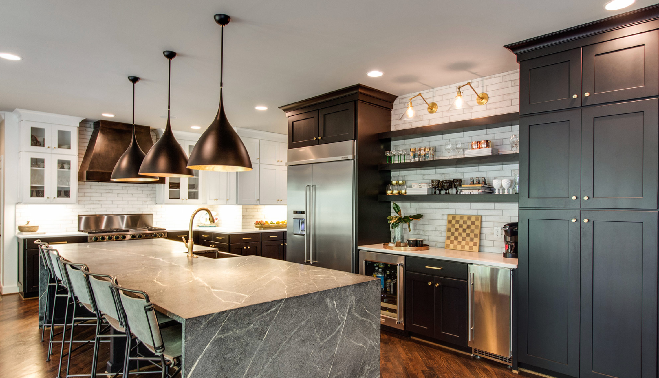 Modern kitchen with black and white cabinetry, a large marble island, black pendant lights, stainless steel appliances, open shelves, and hardwood floors.