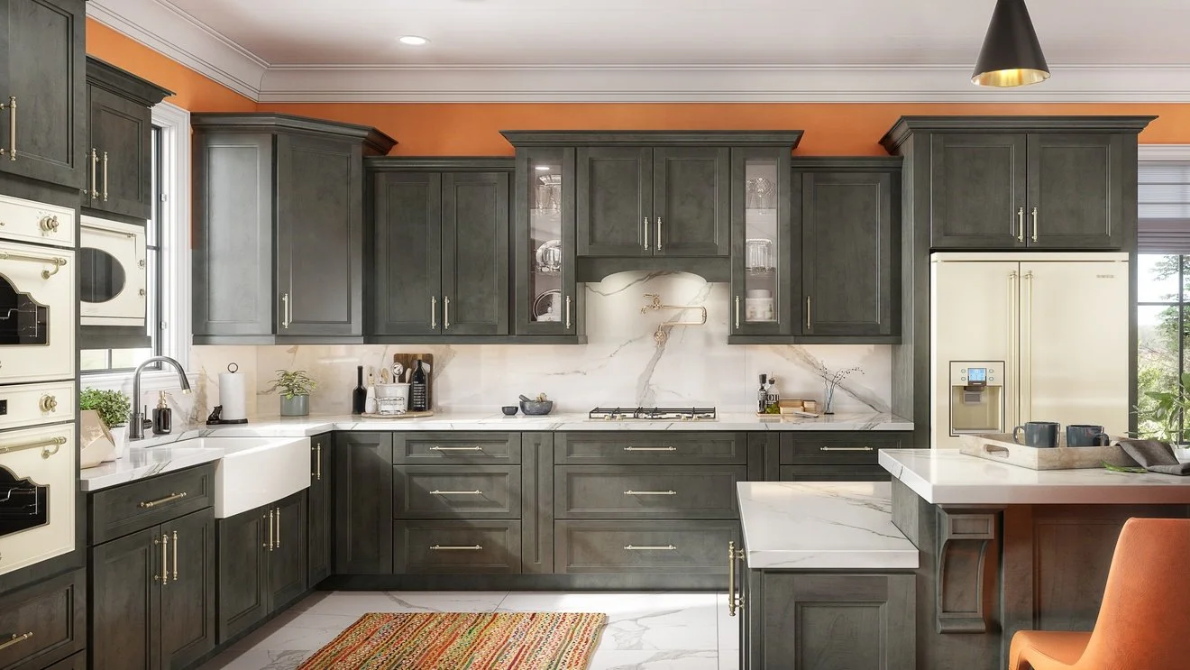 Modern kitchen with dark green cabinets, marble countertops, a white farmhouse sink, and a beige refrigerator, with orange walls, a window, and a black pendant light.